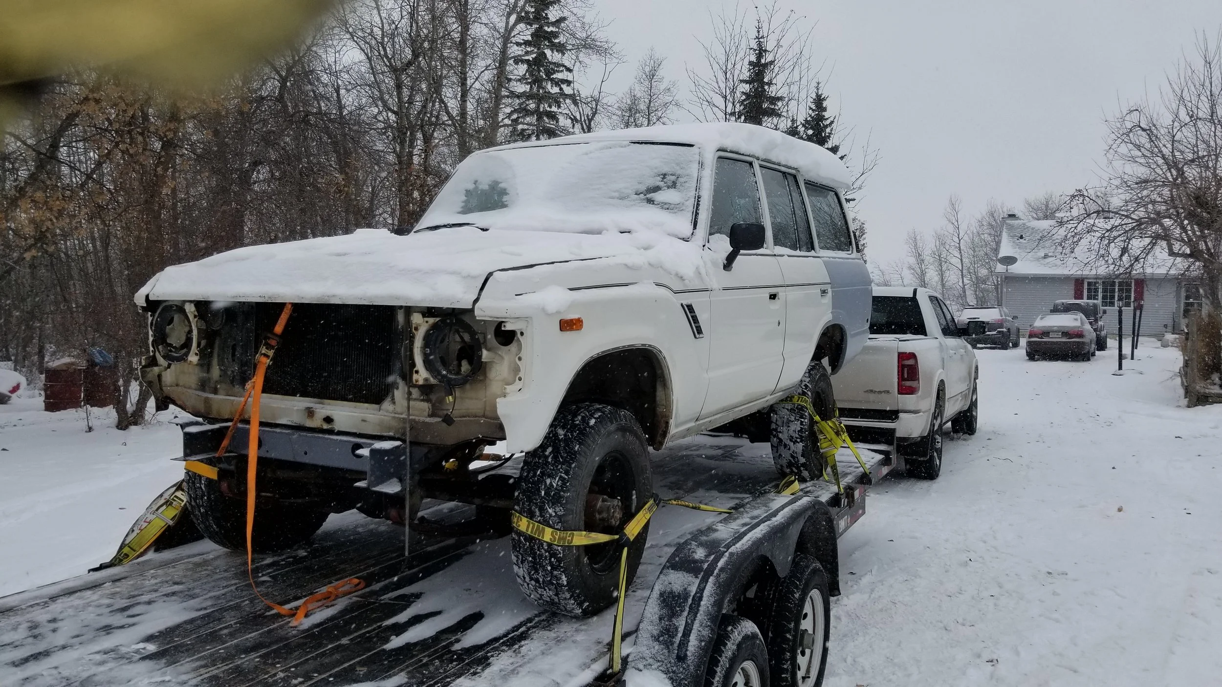 White FJ60 Toyota Landcruiser being hauled on a trailer.