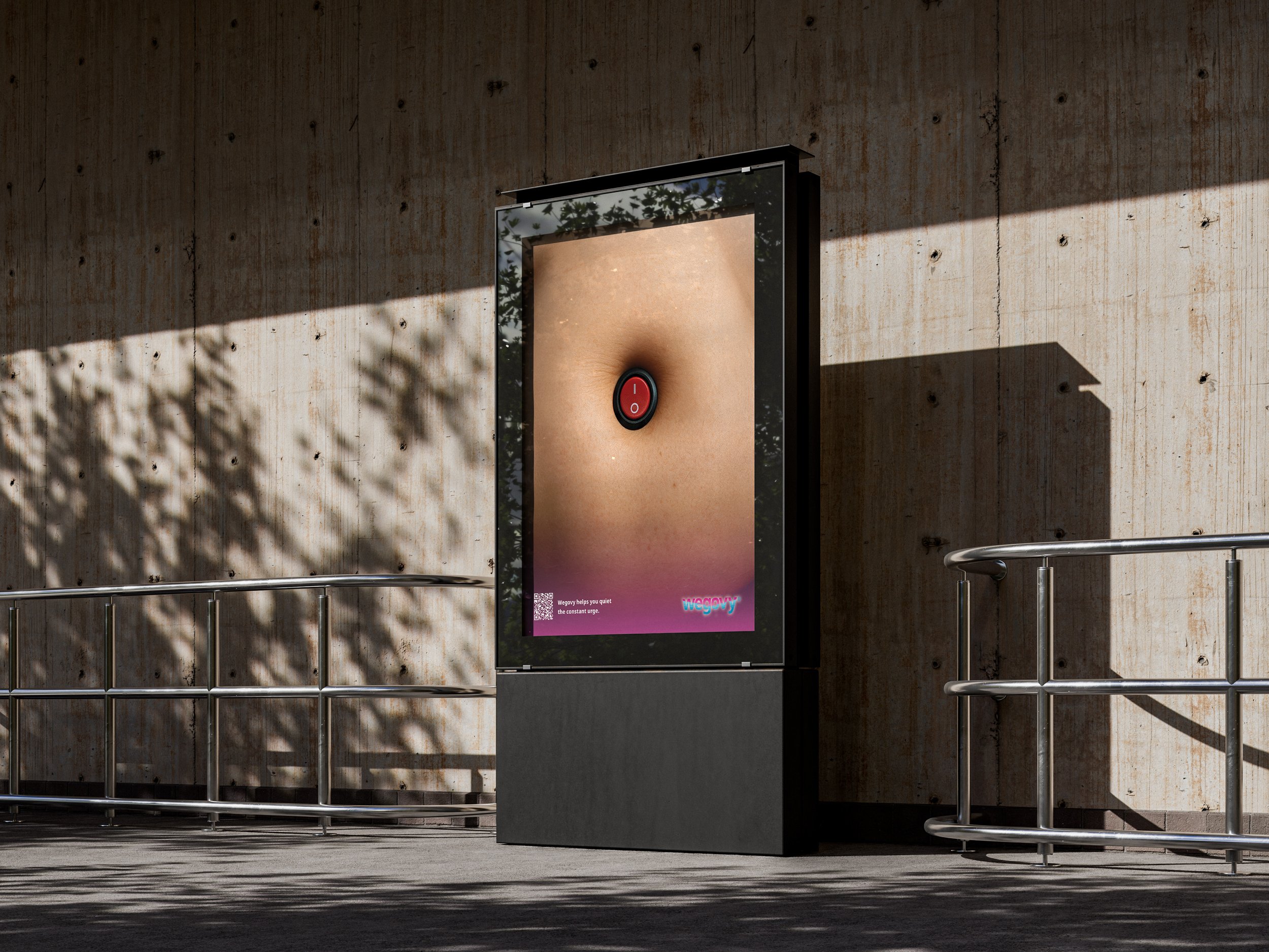 An outdoor advertisement display showing a close-up of a person's navel with a red power button in the center, mounted on a concrete wall with sunlight and shadows.