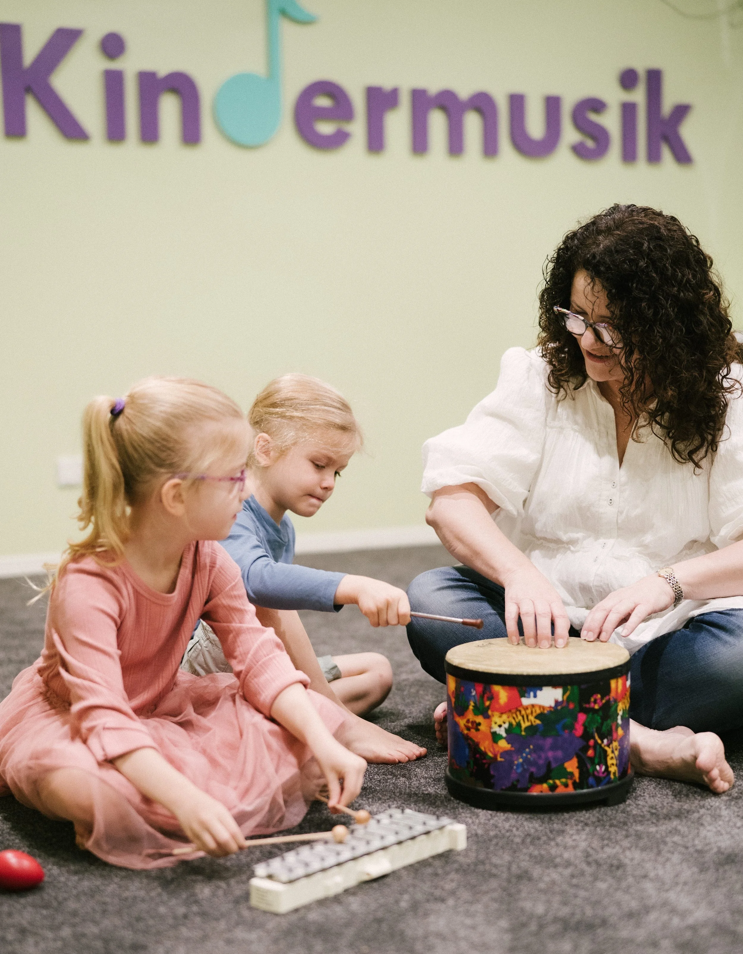Leisa teaching two young girls to play the drums and xylophone at Lesia's Music Place in Toowoomba.