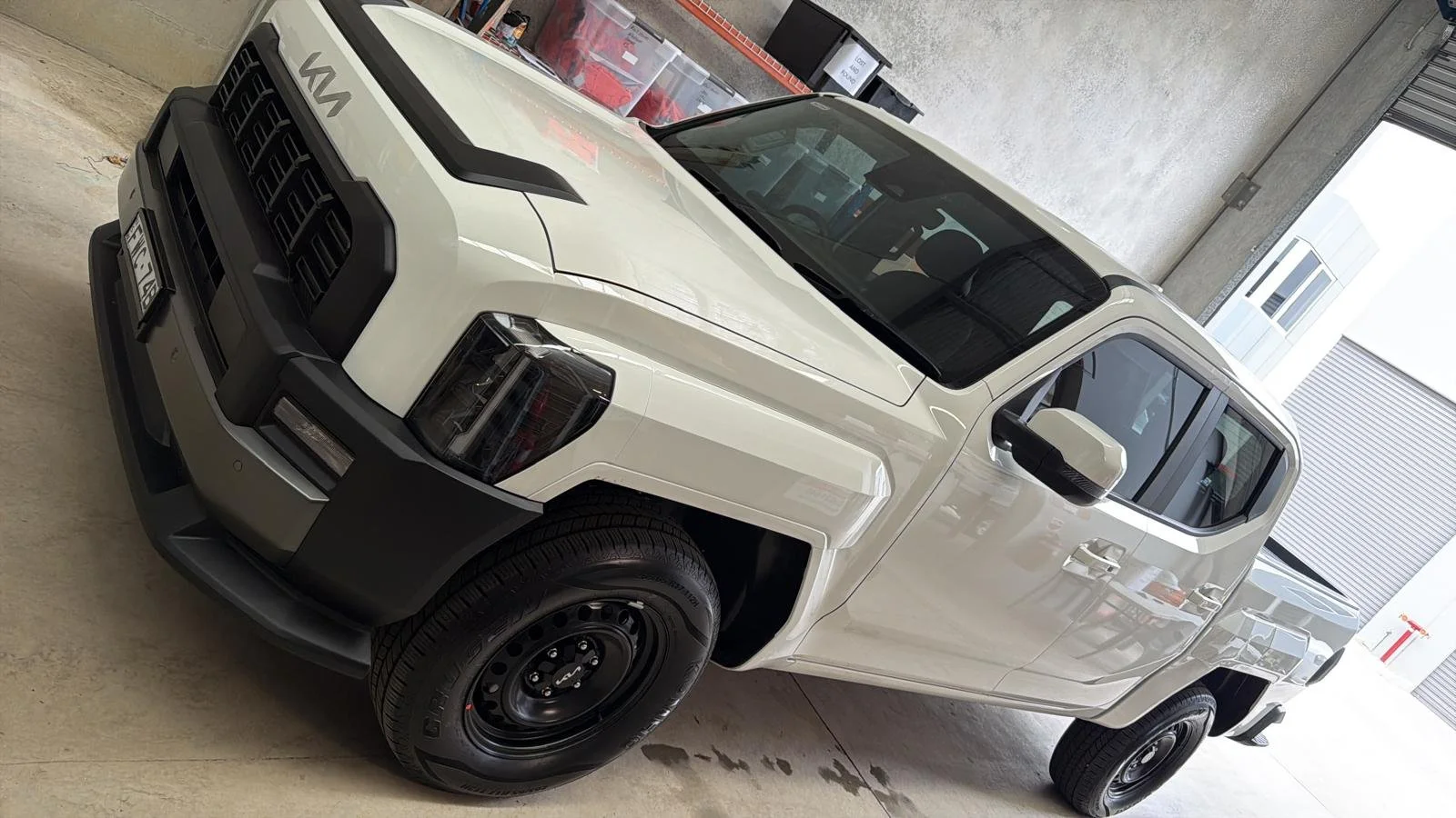 A white pickup truck with black accents parked inside a garage.