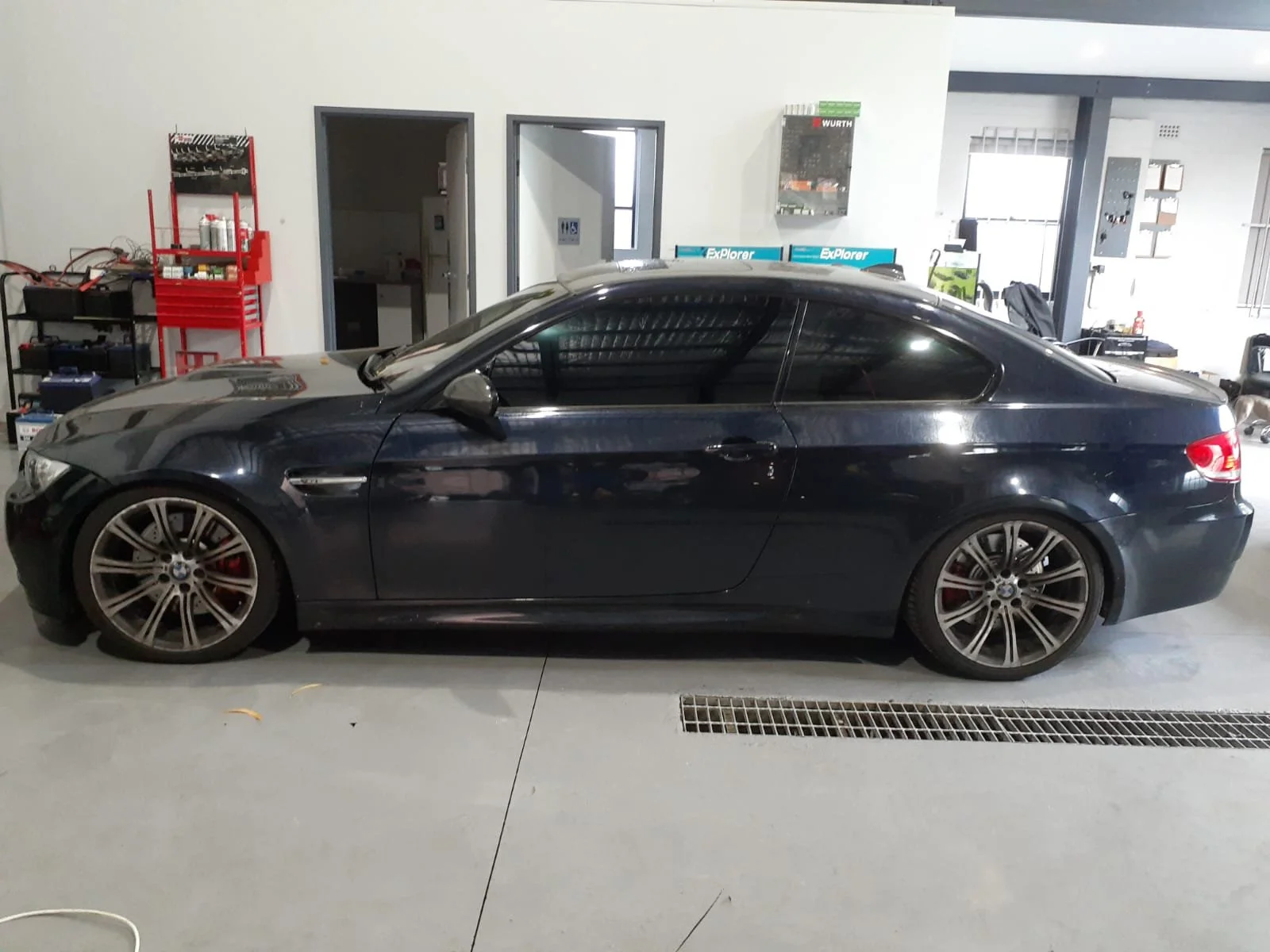 A black BMW coupe parked inside a garage or service area.