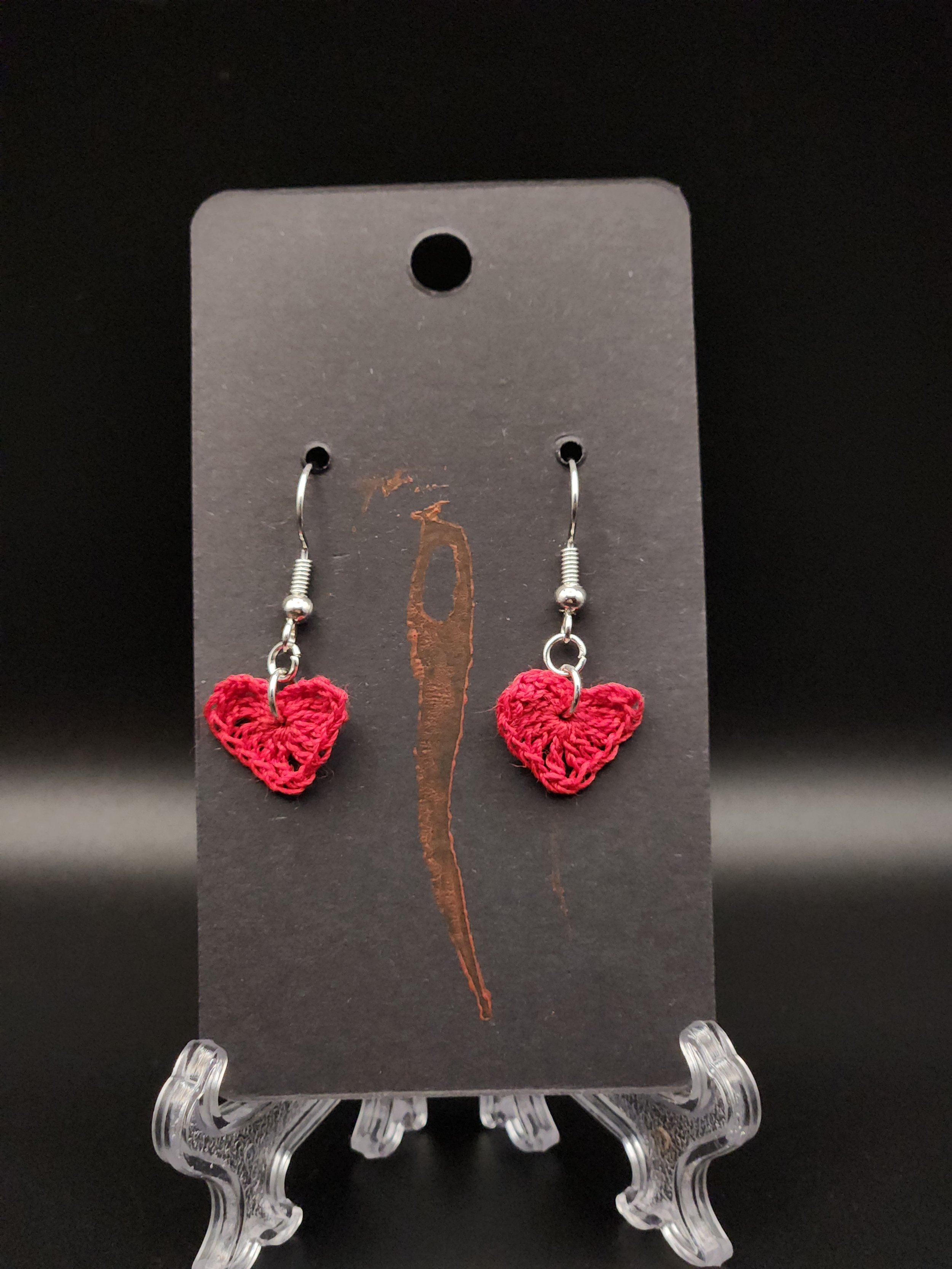 Red crochet heart earrings on black display card with hole at the top for hanging