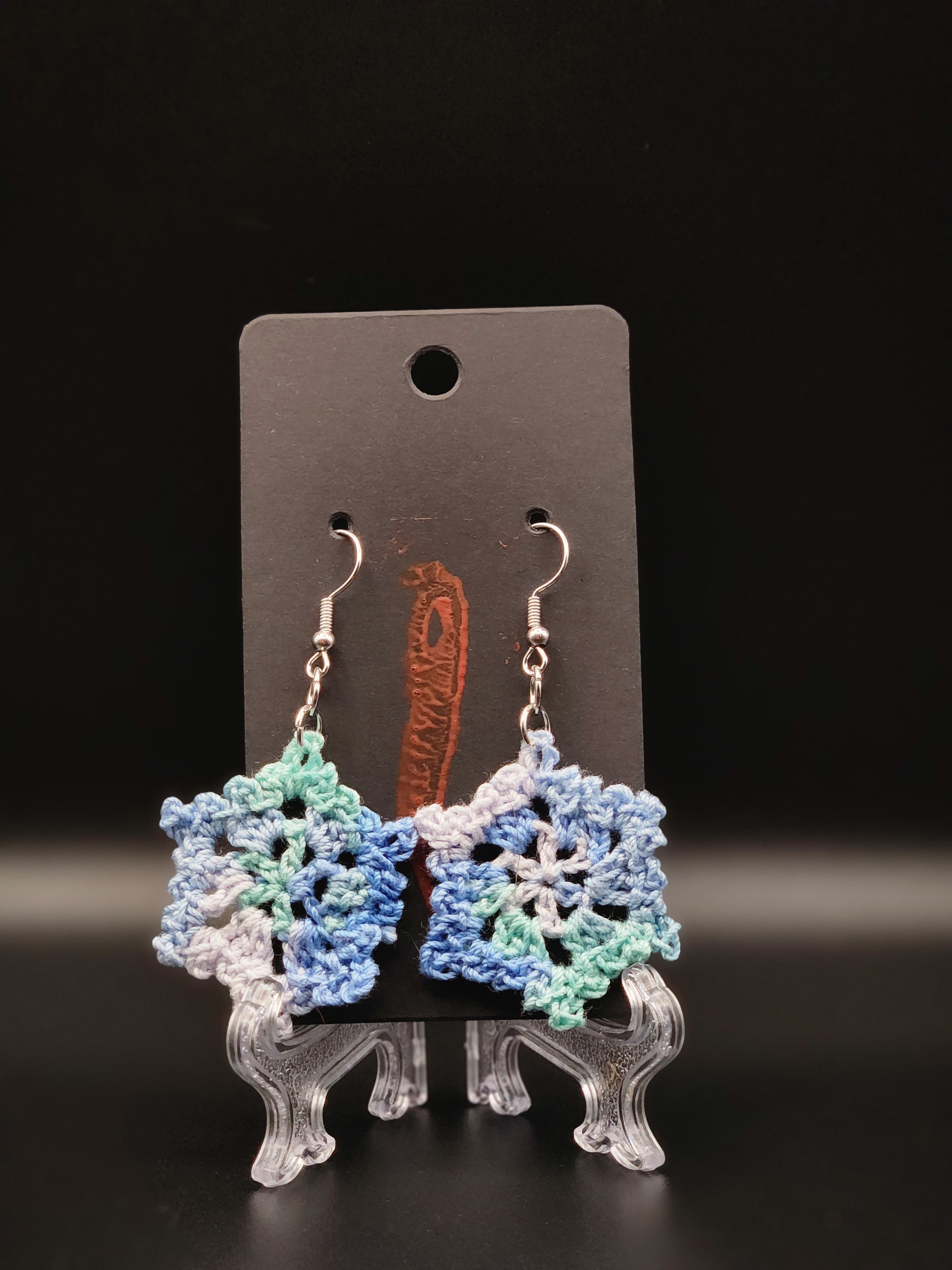 Colorful crocheted butterfly earrings on a display card.