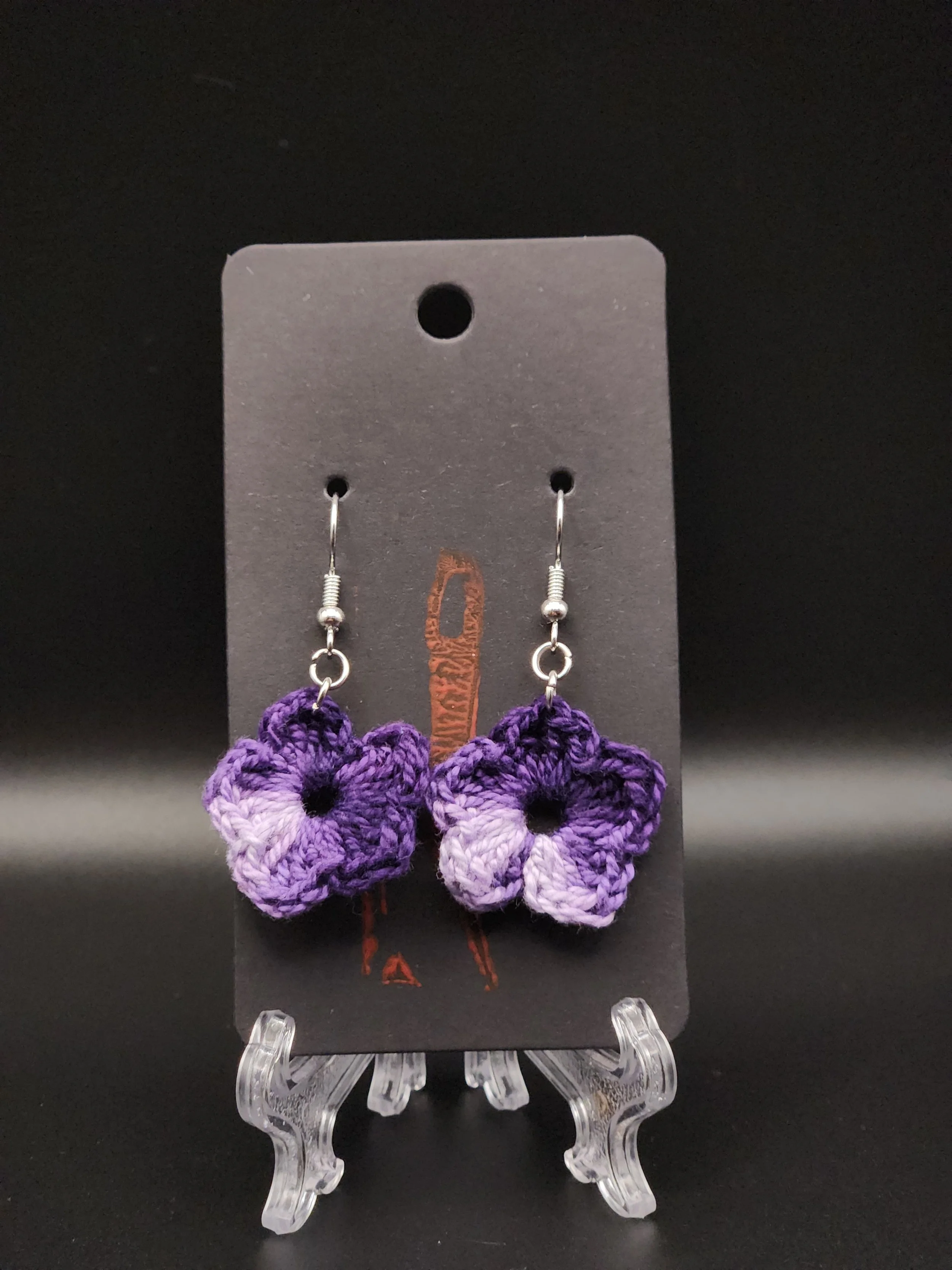 Purple crocheted flower earrings on black display card