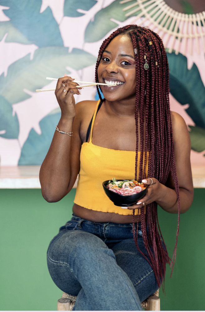A black woman  eating a poke bowl