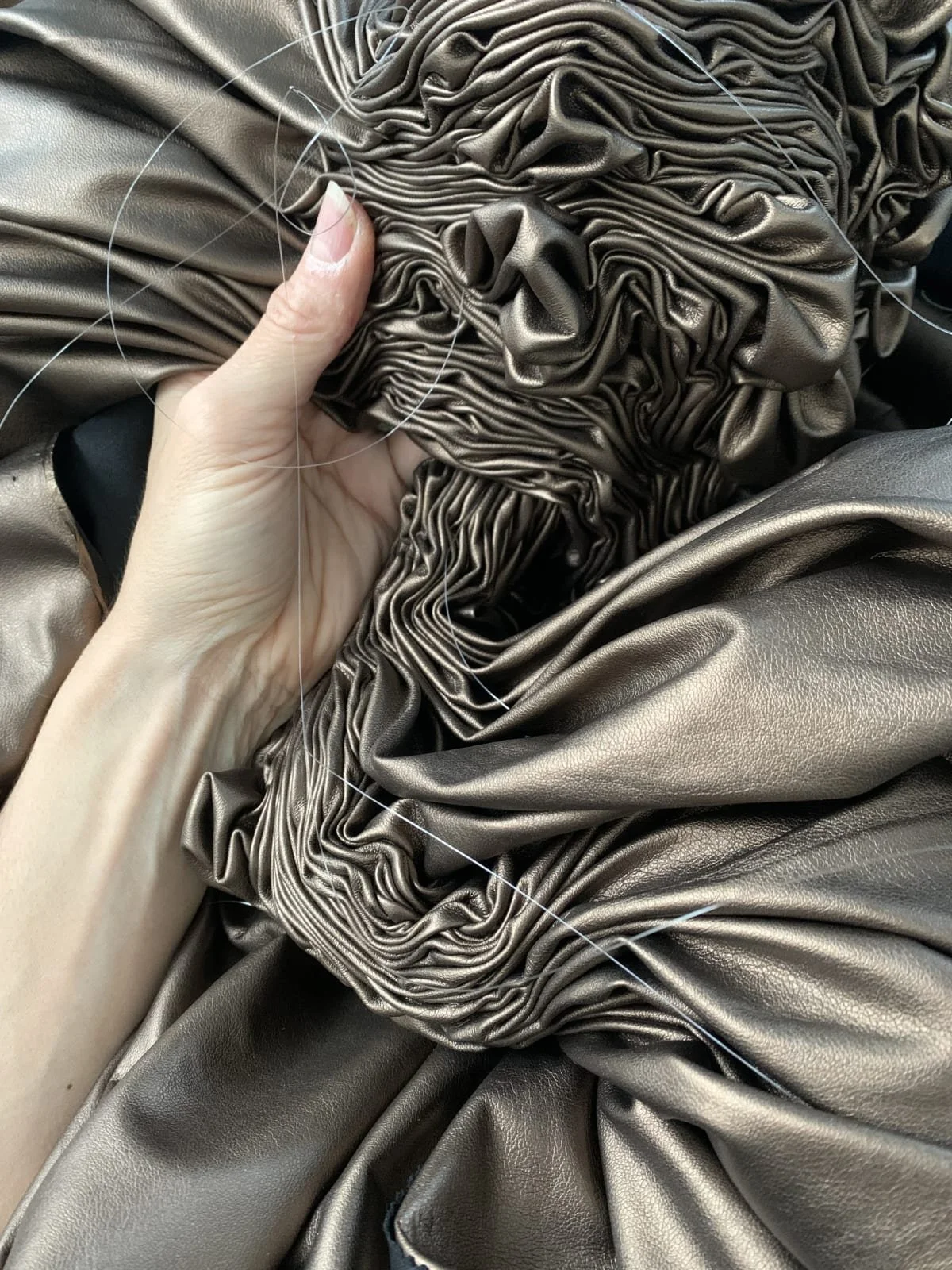 Détail d’Hanne Friis sculptant la matière textile, entre plis, tension et texture.