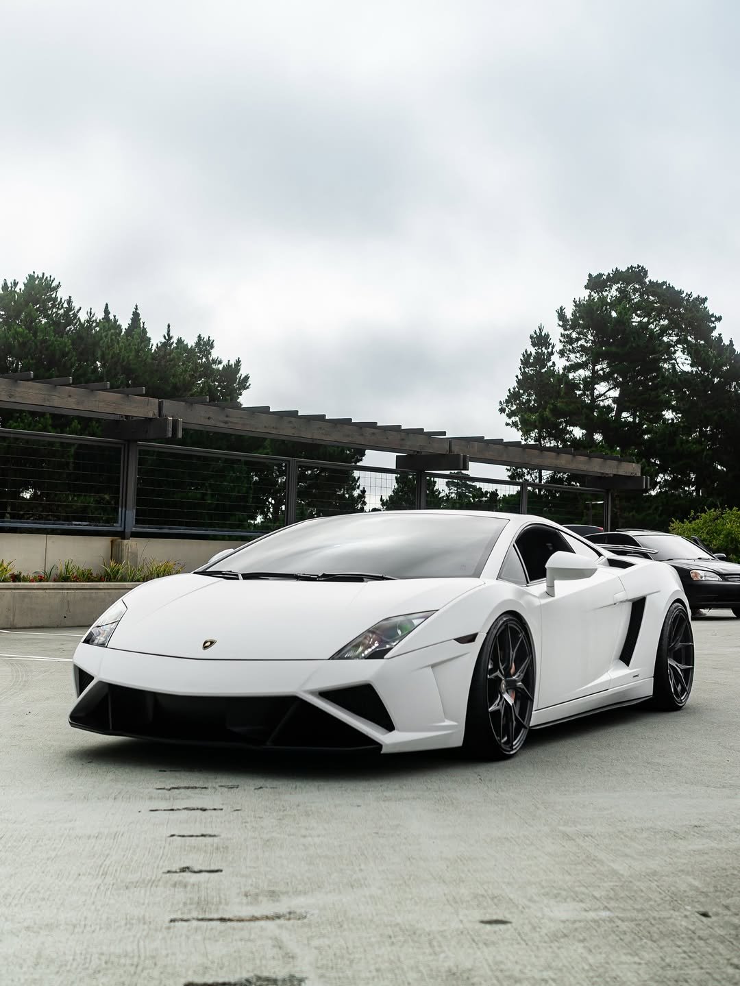 White Lamborghini sports car parked in a parking lot on a cloudy day.