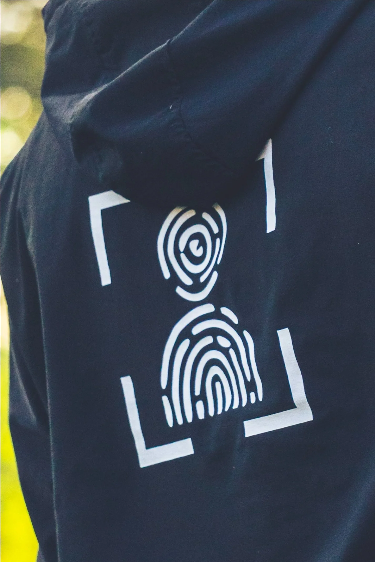 Close-up of a black surface with white fingerprint and handprint patterns, partially visible a white rectangular frame, and a small part of a yellow strip on the left side.