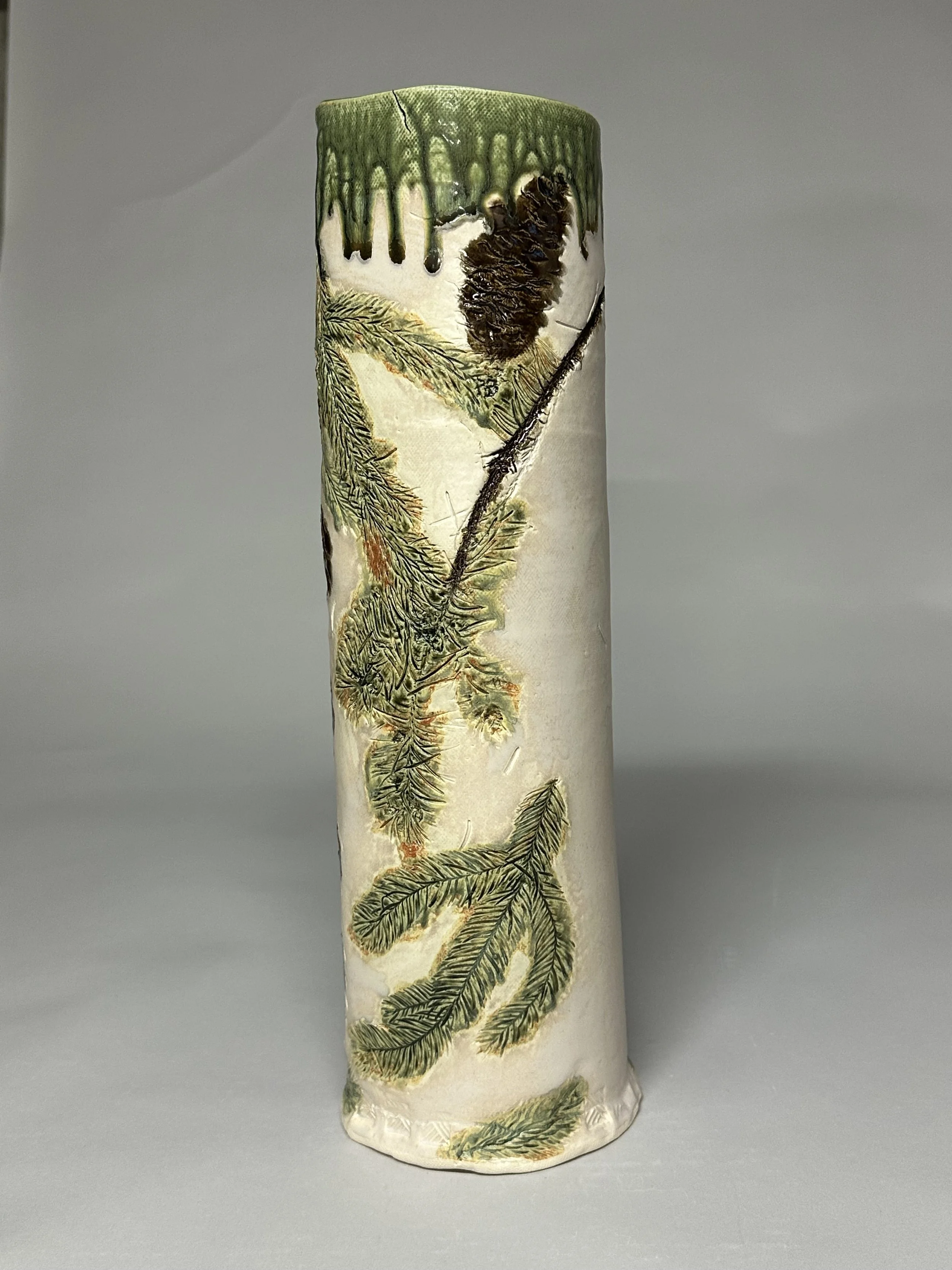 This 16‑inch hand‑built vase features pine and pine cones from Northern Michigan, with a Santorini Green glaze on the inside and a warm oatmeal finish on the outside for a soft, natural contrast.