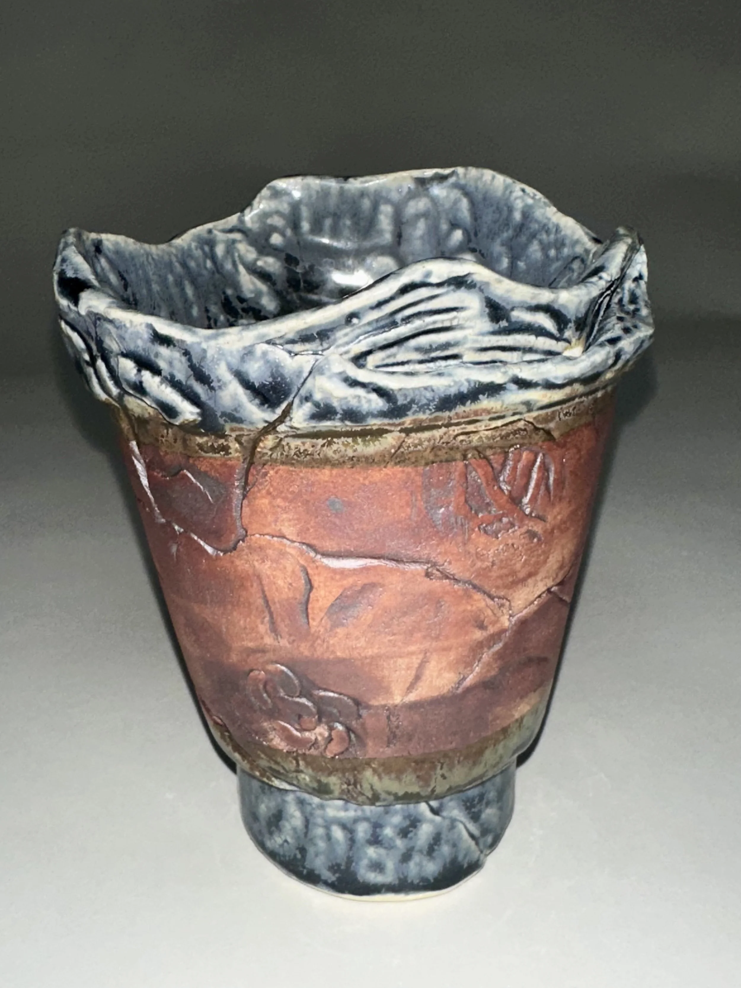 Made by hand with a layered porcelain clay technique, this flower pot blends multicolored glaze work with hand‑stamped textures achieved through mostly custom, studio‑made stamps. The sculptural rim and carved motifs create a striking home for succul