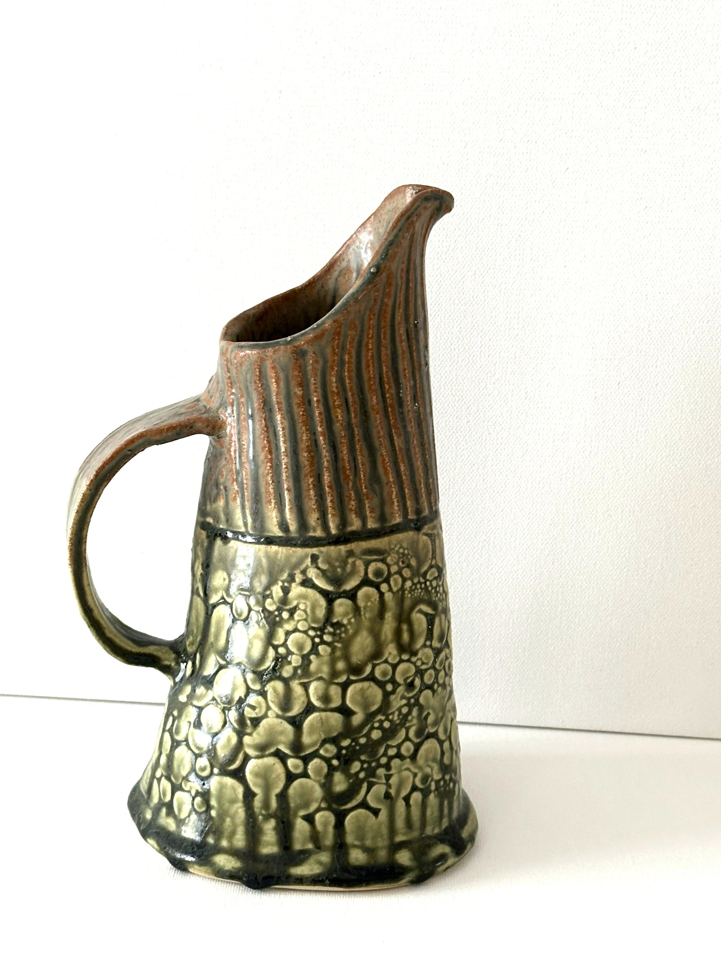This lovely porcelain clay pitcher can be used to hold beverages. It is finished with a Santorini Ash glaze.
