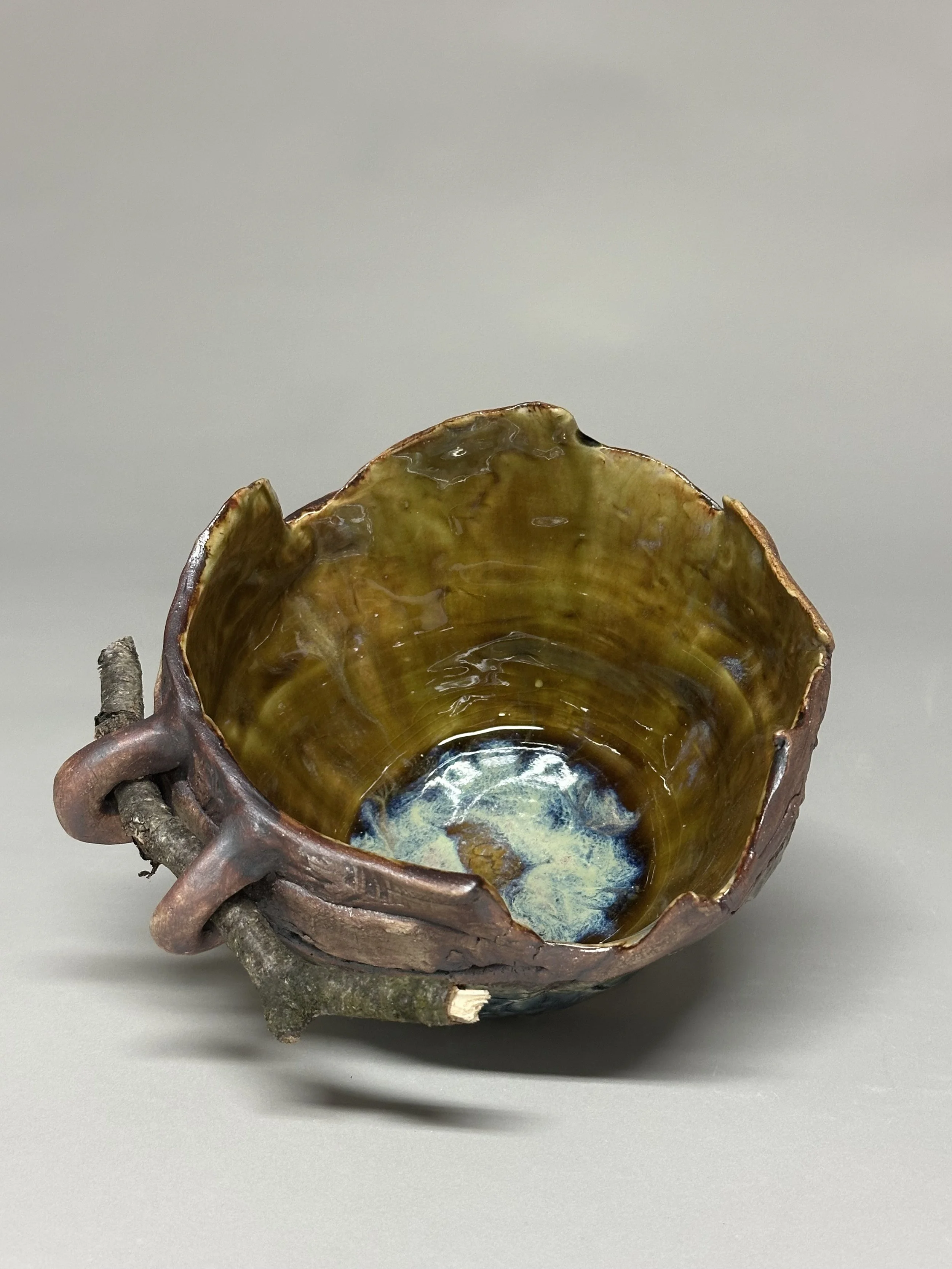A handcrafted bowl glazed with iron oxide, Blue Ash, and eight layered glazes, finished with handmade stamps and a small birch branch to honor Michigan.