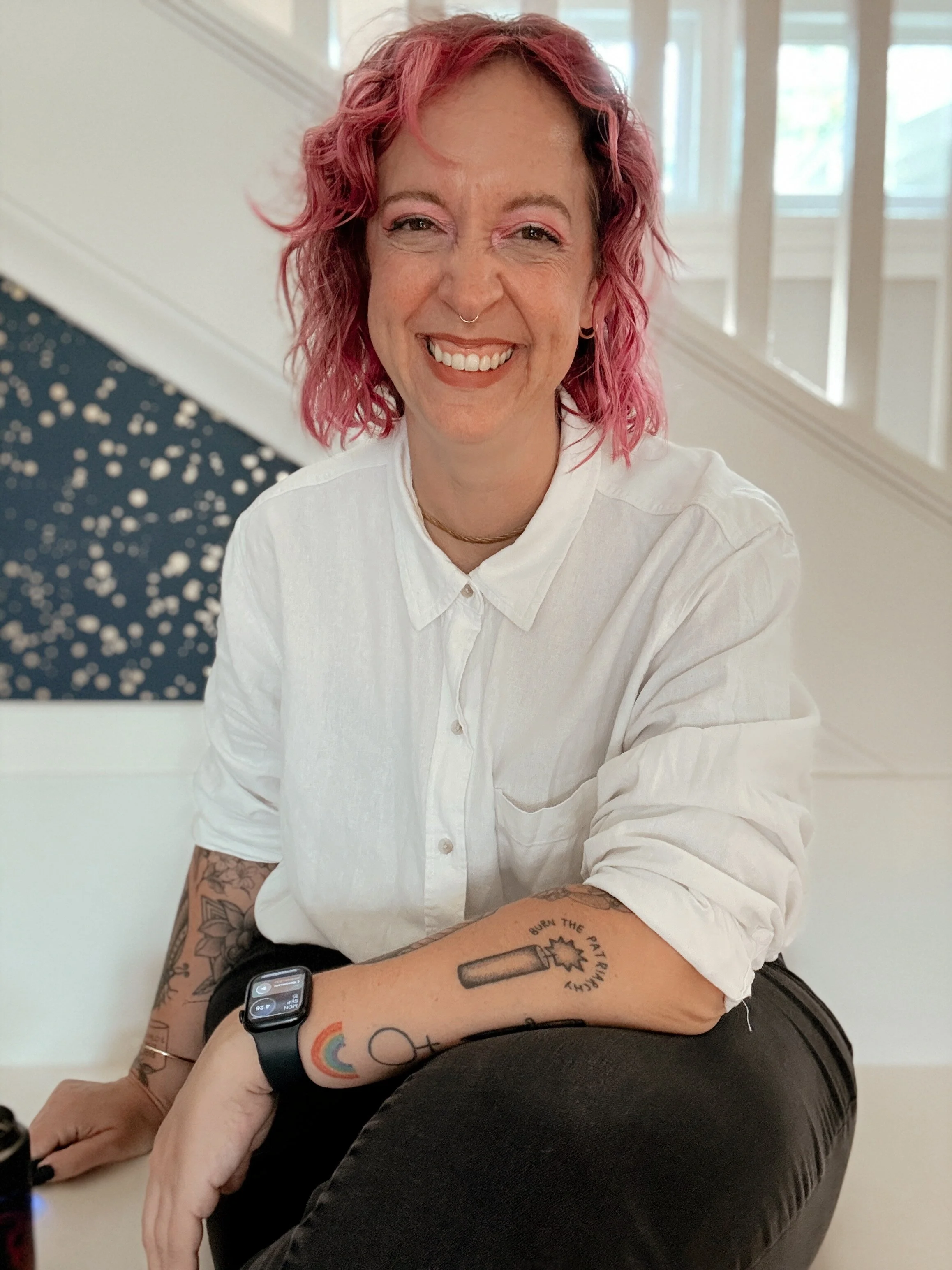 Neurodivergent ADHD Autistic woman Crystal Britt in white shirt and black pants, with pink hair. She is smiling.