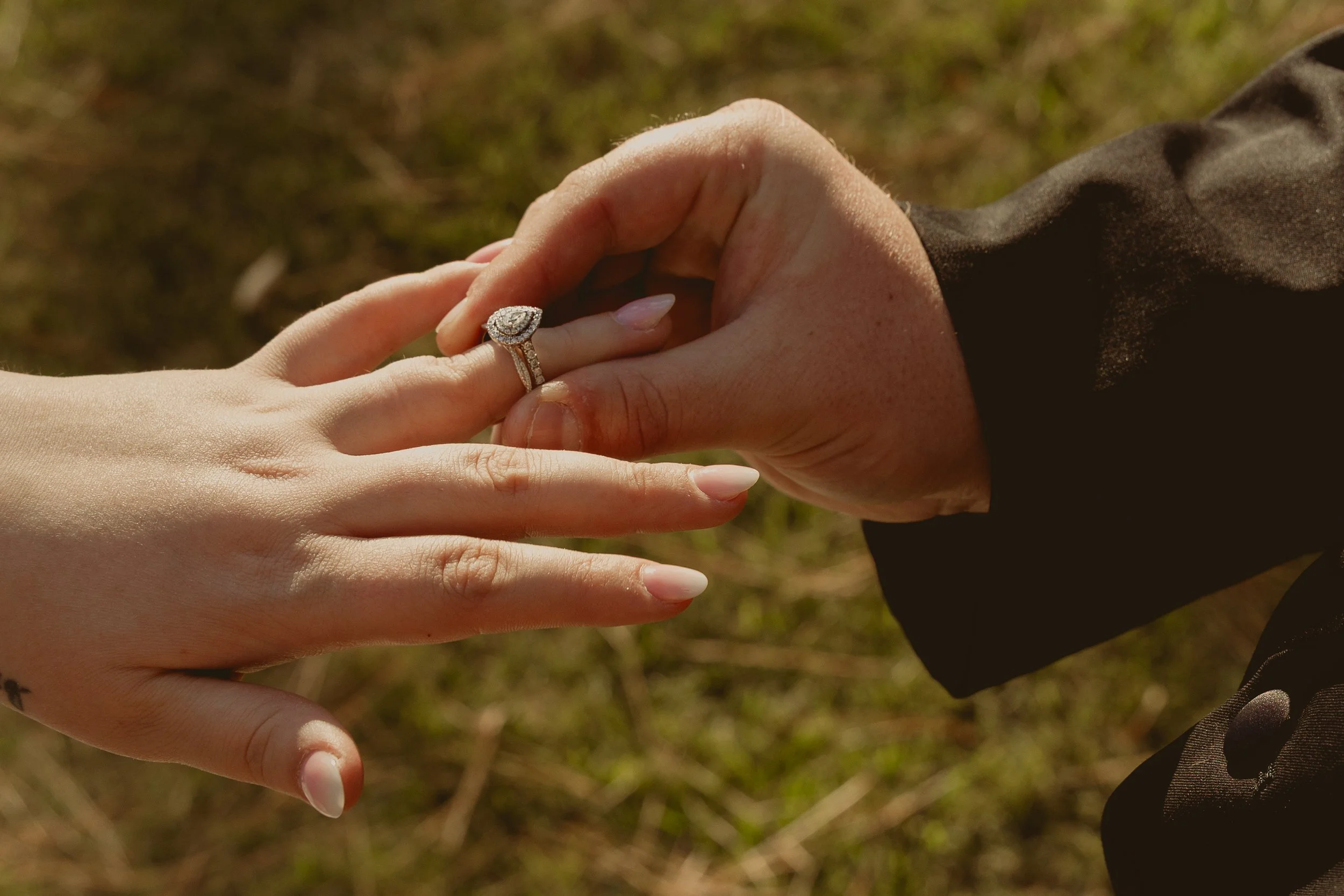 Close-up of a hand with a wedding ring being held by another person's hand outdoors. Editorial style wedding photography in Alabama.