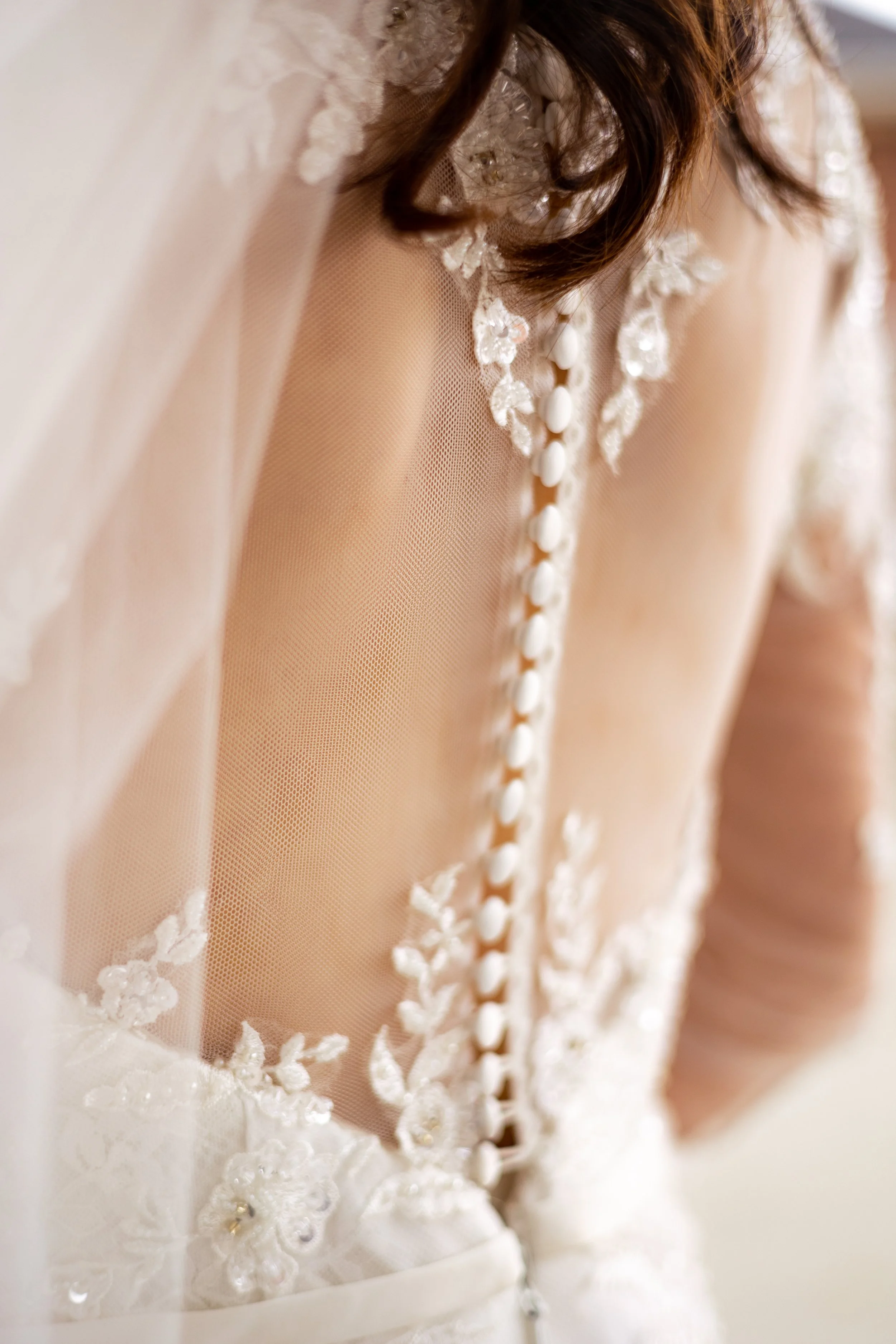 Close-up of a wedding dress with lace details and buttons on the back.