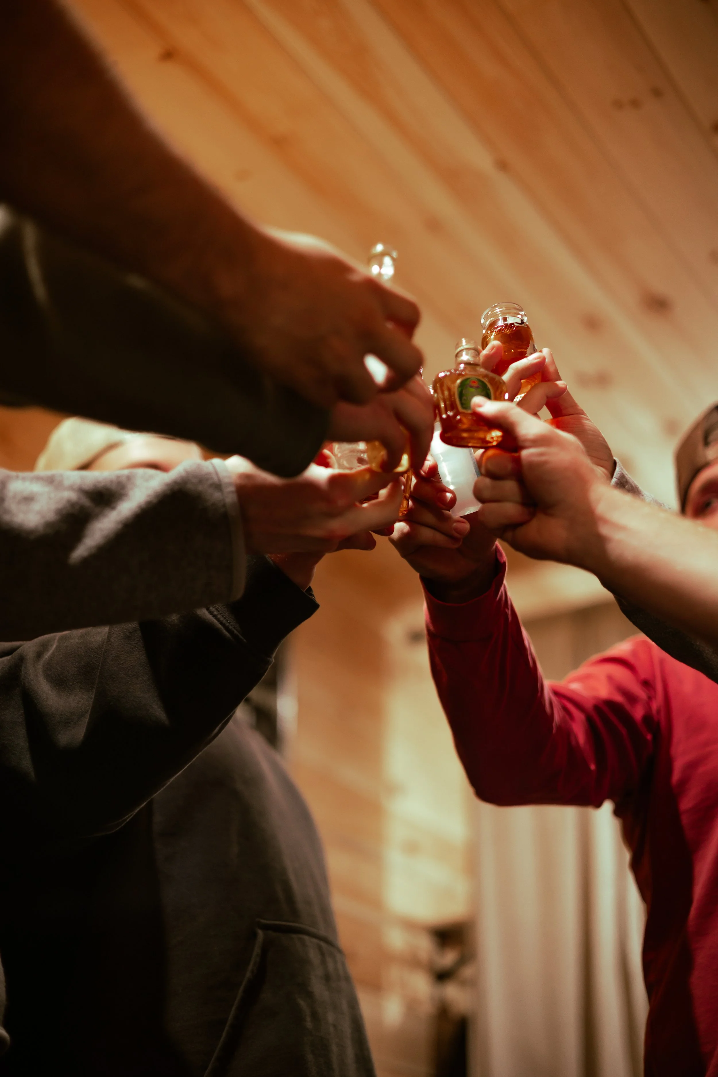 People clinking small glasses, with a wooden ceiling in the background celebrating a groom getting ready for his wedding day. Wedding photographer in Mississippi.