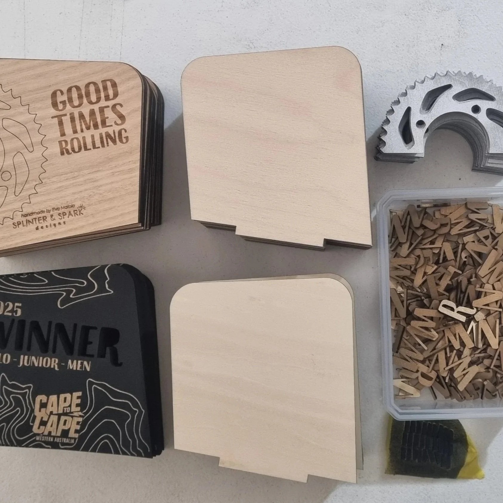 Stacked wooden cards with text, metal and wooden components, and small letter pieces in a container.