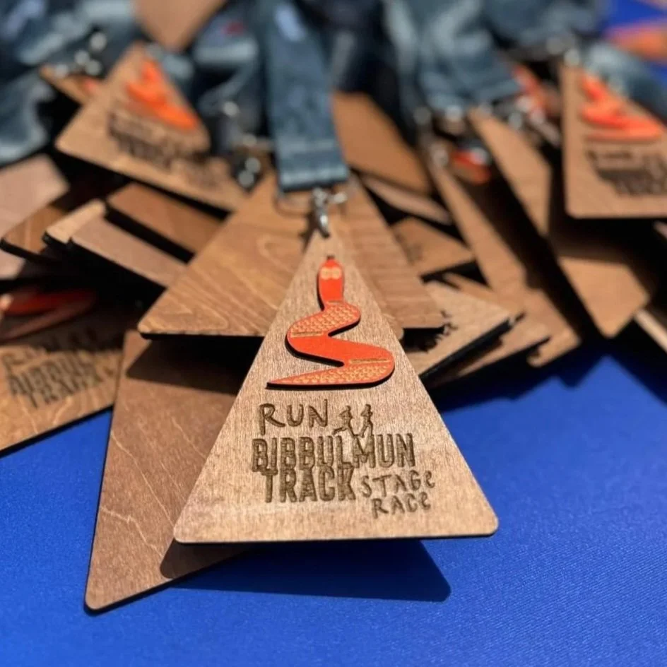 Wooden medals with orange snake logo and text for Bubble/Mun Track Stage Race.