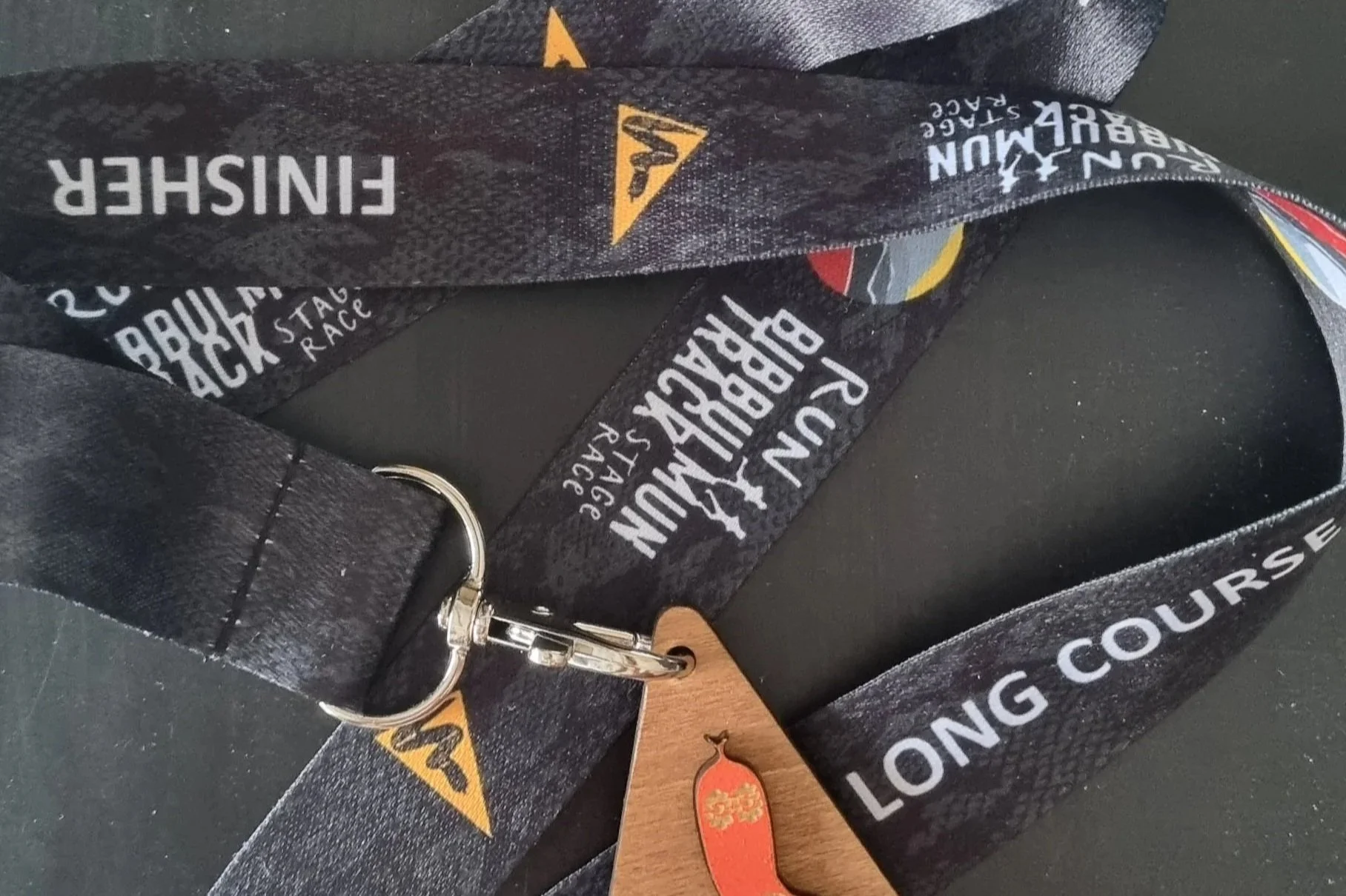 Black lanyard with white text reading 'LONG COURSE' and 'SUBARU BACKSTAGE' with a Subaru logo, attached to a metal clip and a wooden tag.