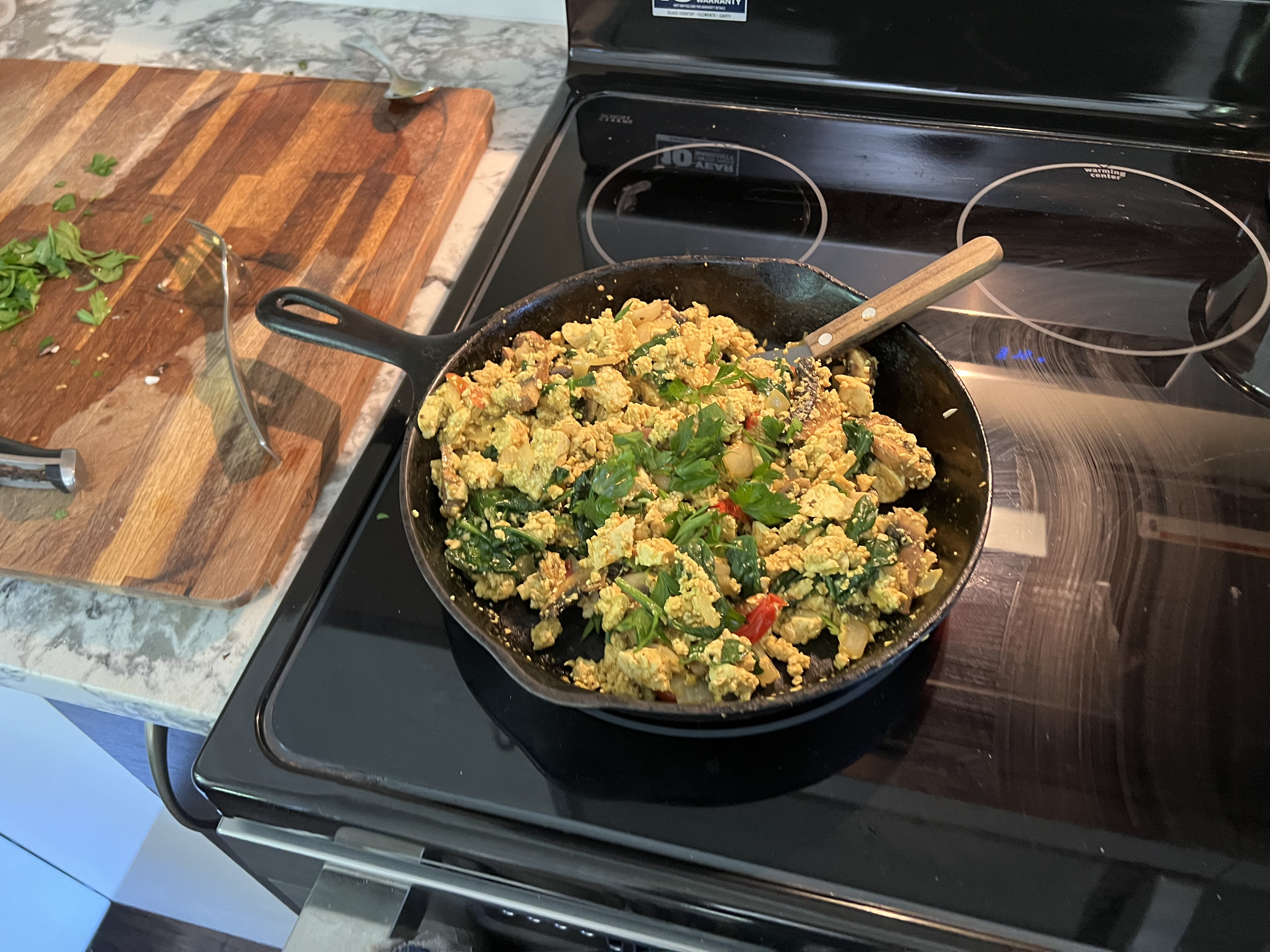 Tofu scramble with fresh parsley, sautéed baby tomatoes and spinach, seasoned with turmeric, chili and curry powder