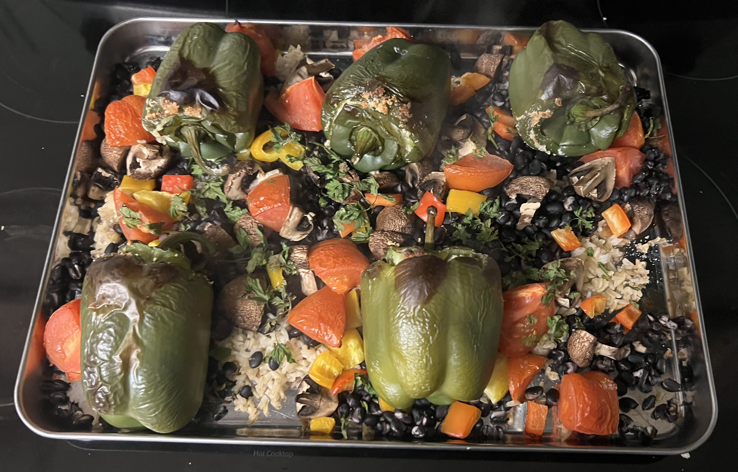 homemade stuffed peppers with vegan ricotta, black beans, baked tomatoes, potatoes and rice