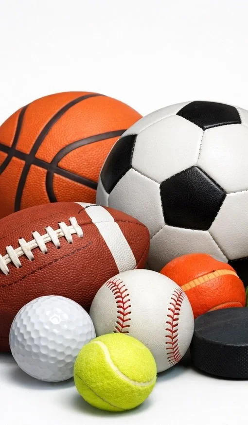 A collection of various sports balls including a basketball, soccer ball, American football, baseball, tennis ball, golf ball, and a hockey puck.