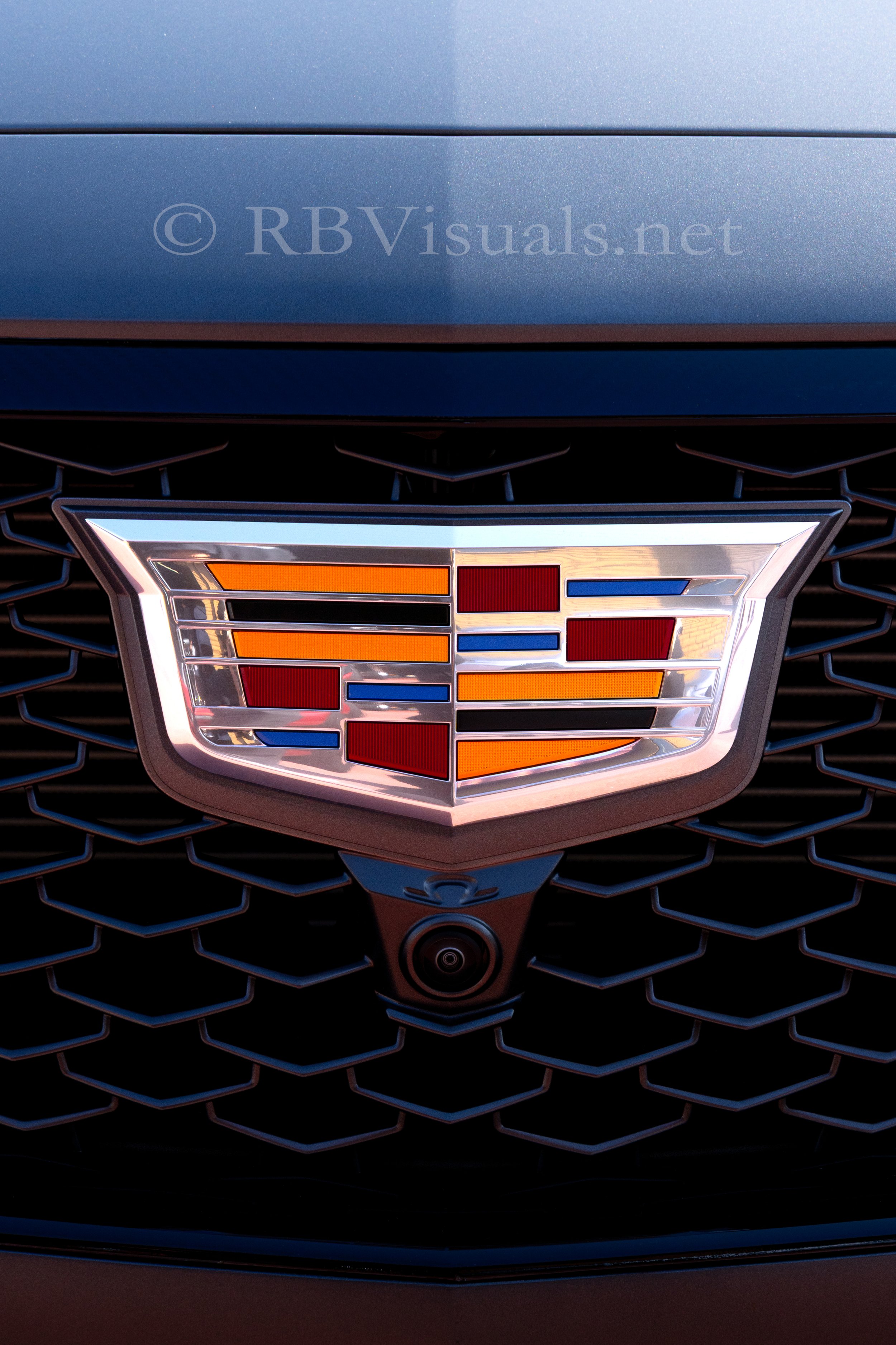 Front grille of a Cadillac vehicle featuring the Cadillac emblem and a camera below it.