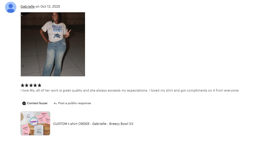 A woman wearing a white Breezy Bowl T-shirt with a logo, standing outdoors on a sidewalk, posing with a peace sign and smiling.