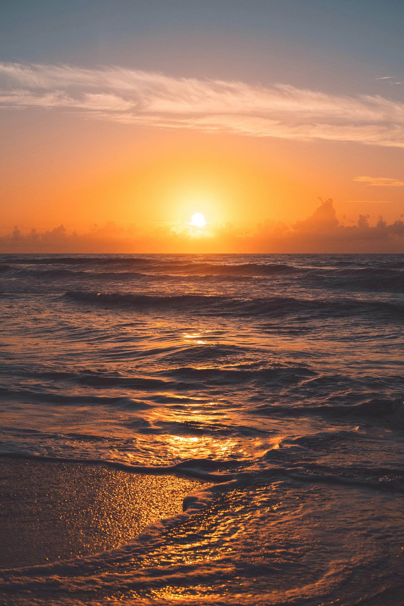 Sunset over the ocean with clouds and shimmering water reflections