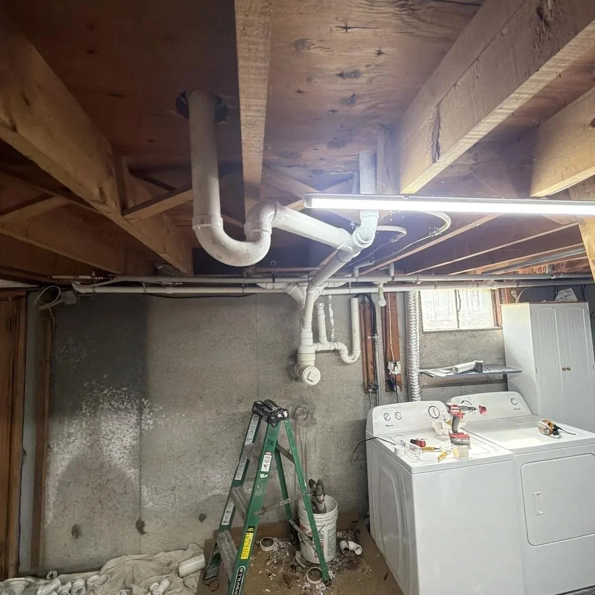 New PVC drain and vent lines installed in basement laundry area
