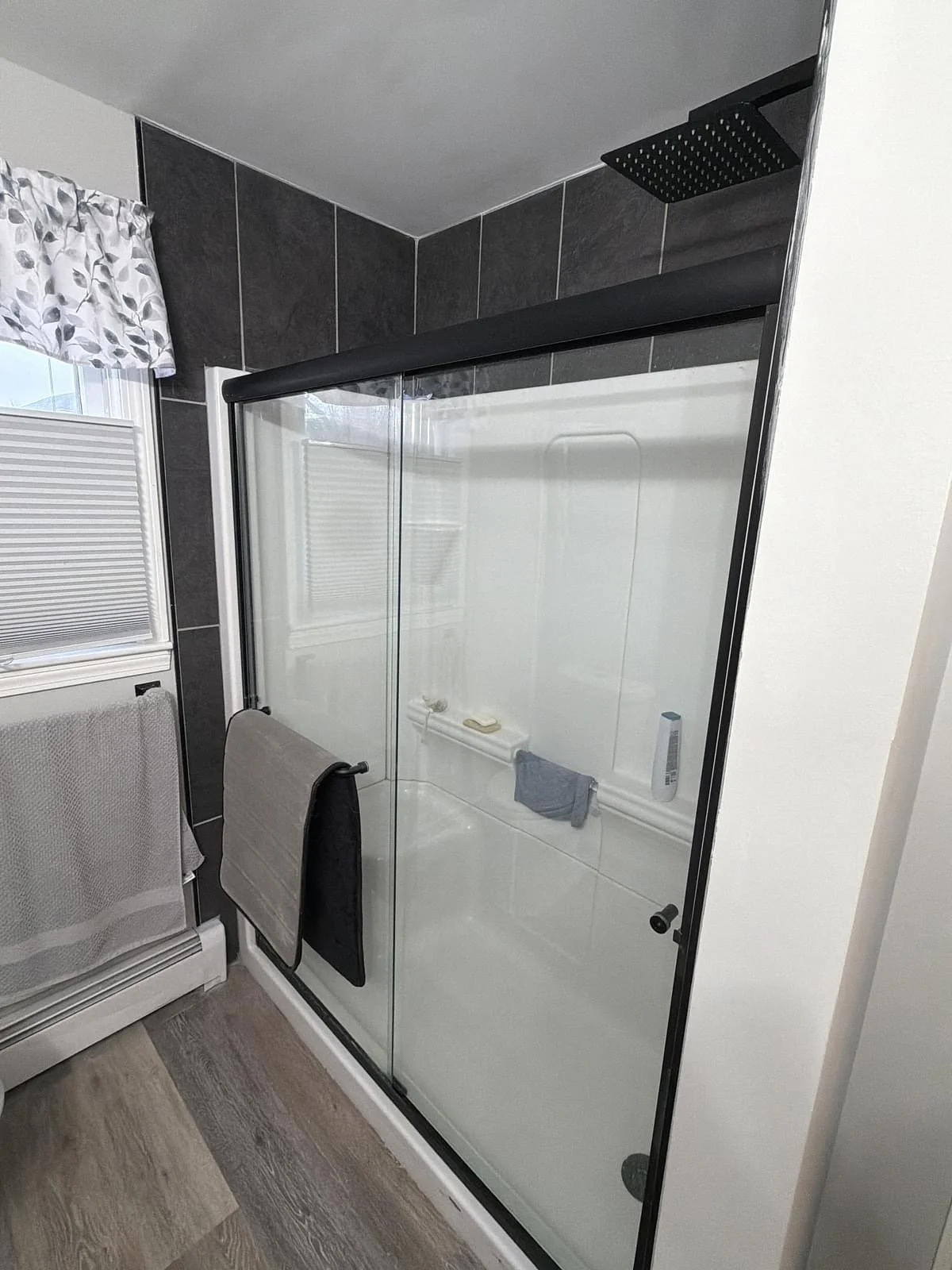 Finished walk-in shower with glass slider, matte black hardware and rain shower head