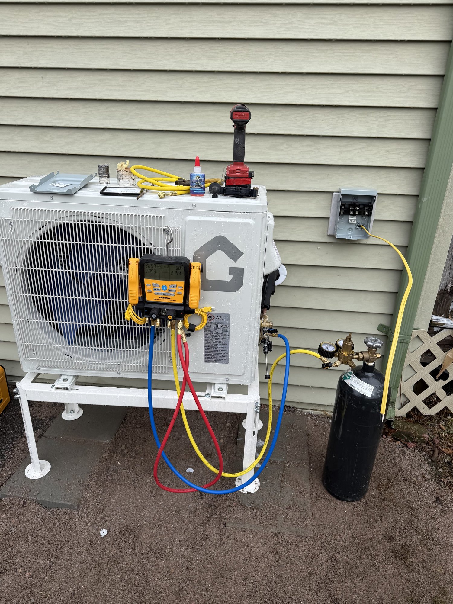 Mini-split heat pump condenser installation with pressure testing gauges
