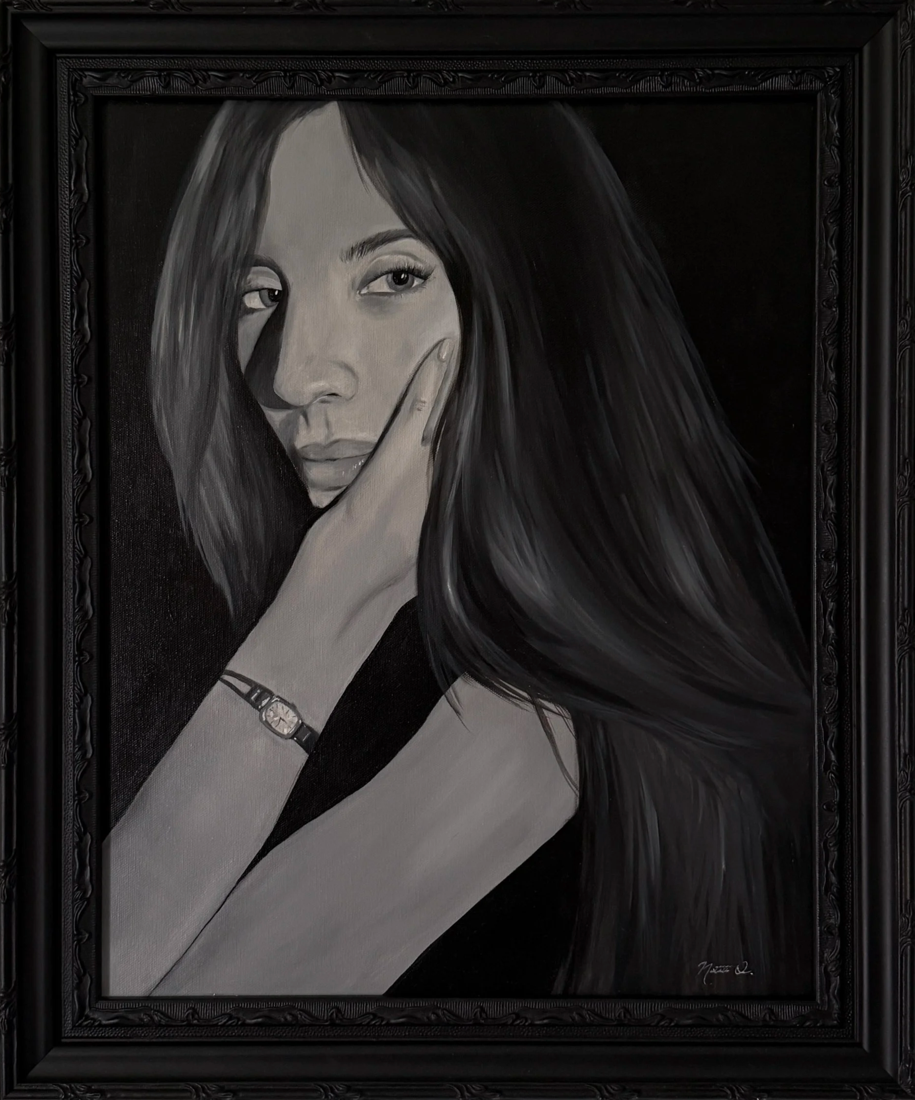 Black and white portrait of a woman with long hair, resting her face on her finger, wearing a necklace, framed in an ornate black frame.