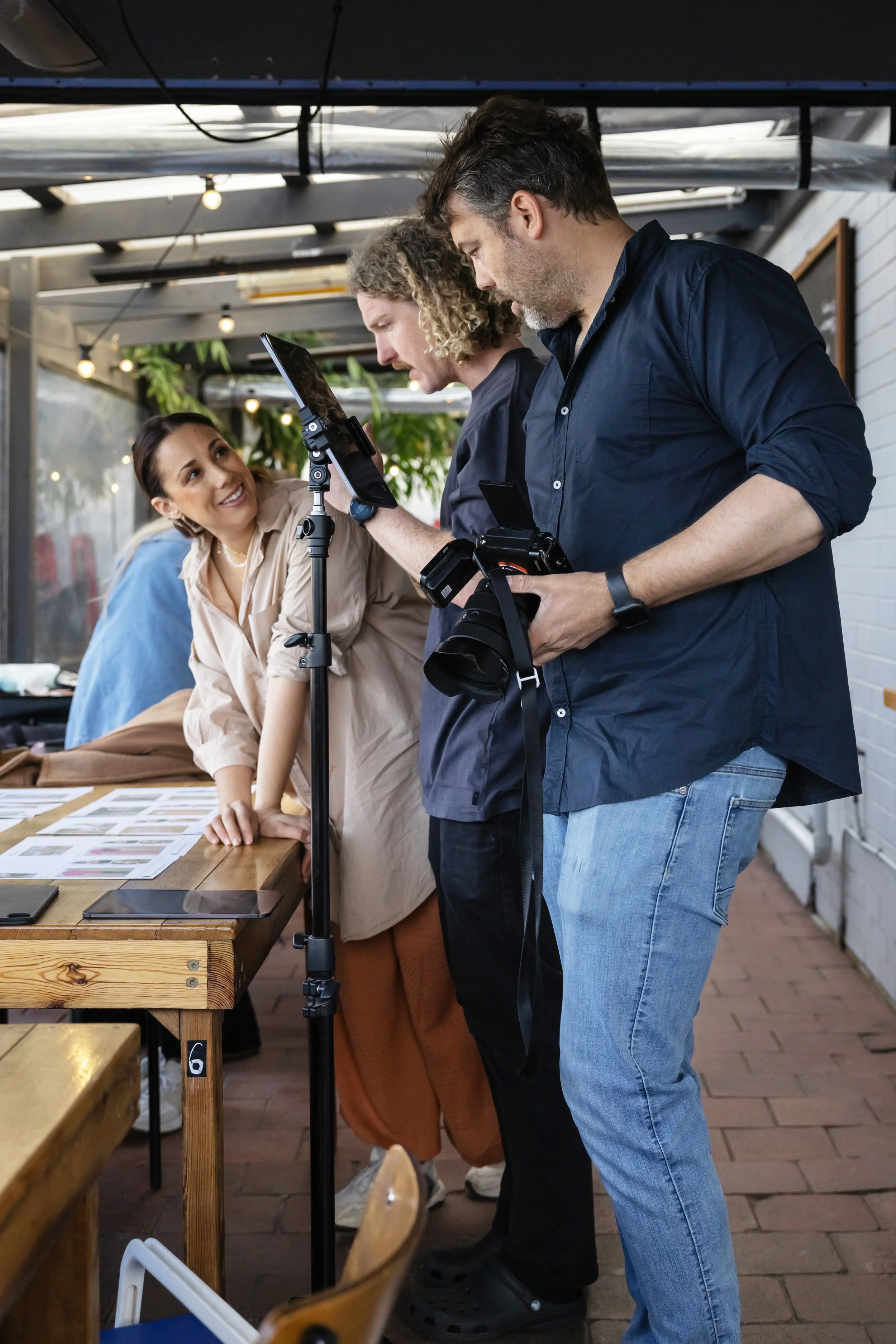 Creative team at a photoshoot in a cafe with wooden tables and string lights.