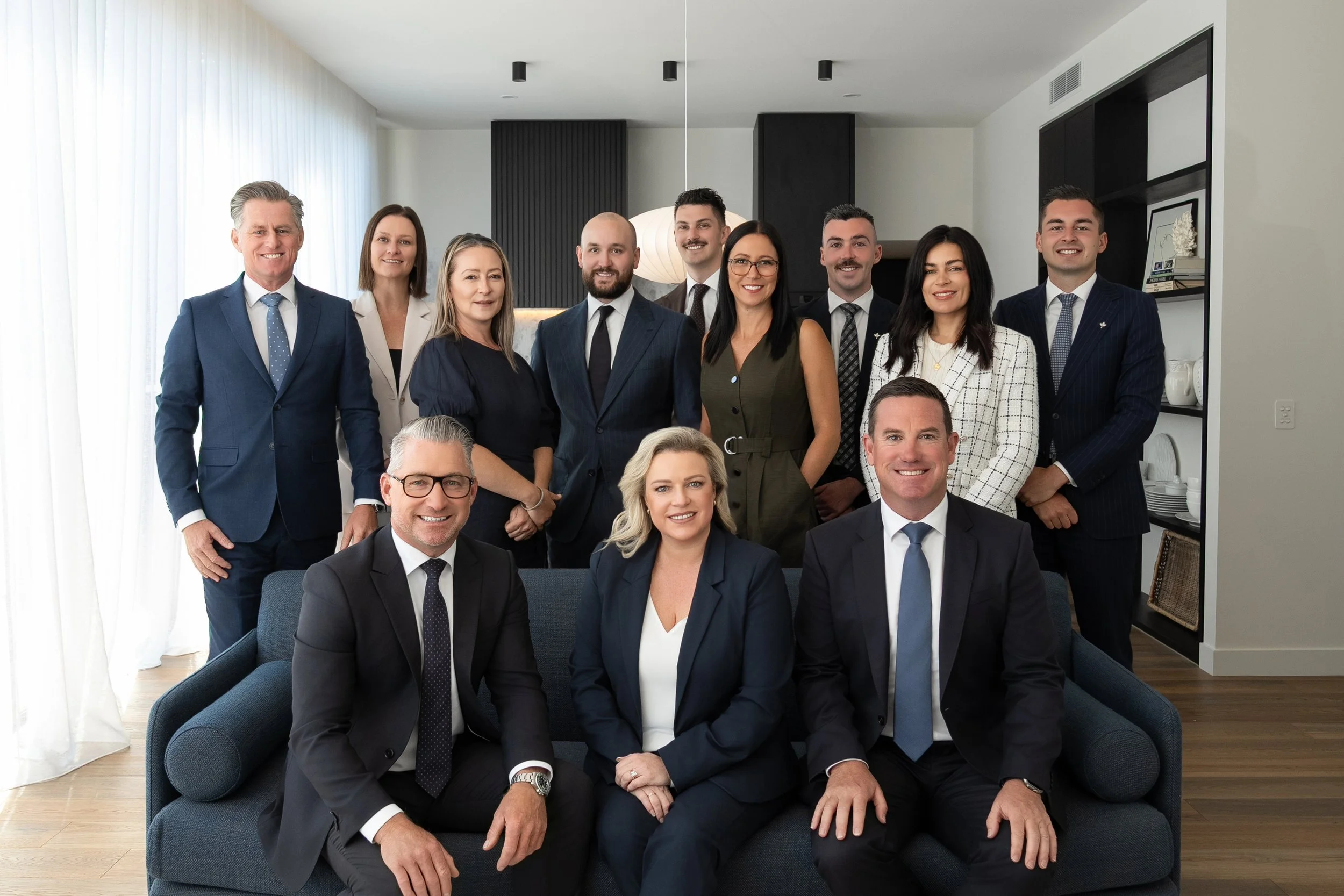 Business team of professionals in formal attire posing in a modern office.