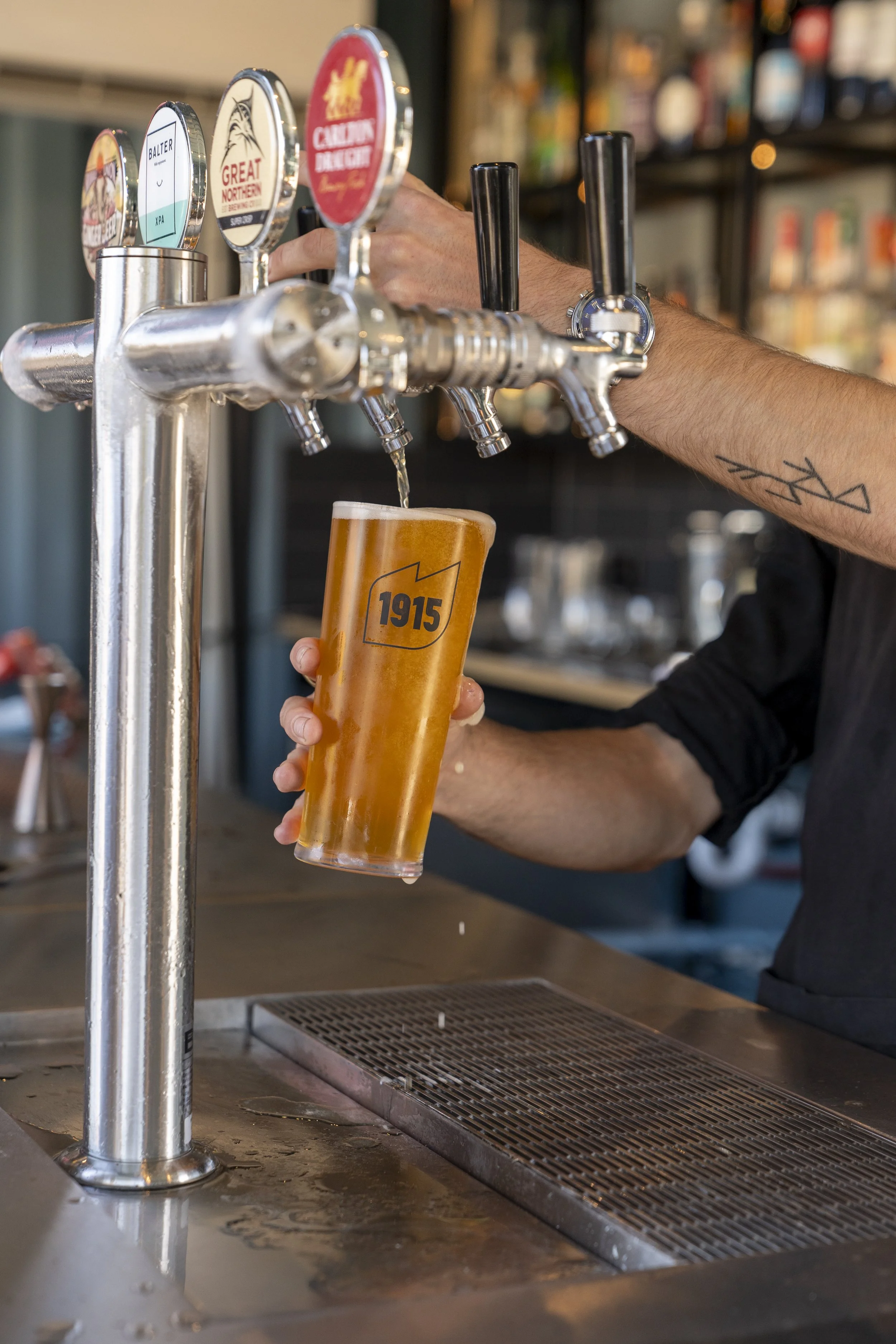 A bartender is pouring a glass of beer from a tap at a bar.