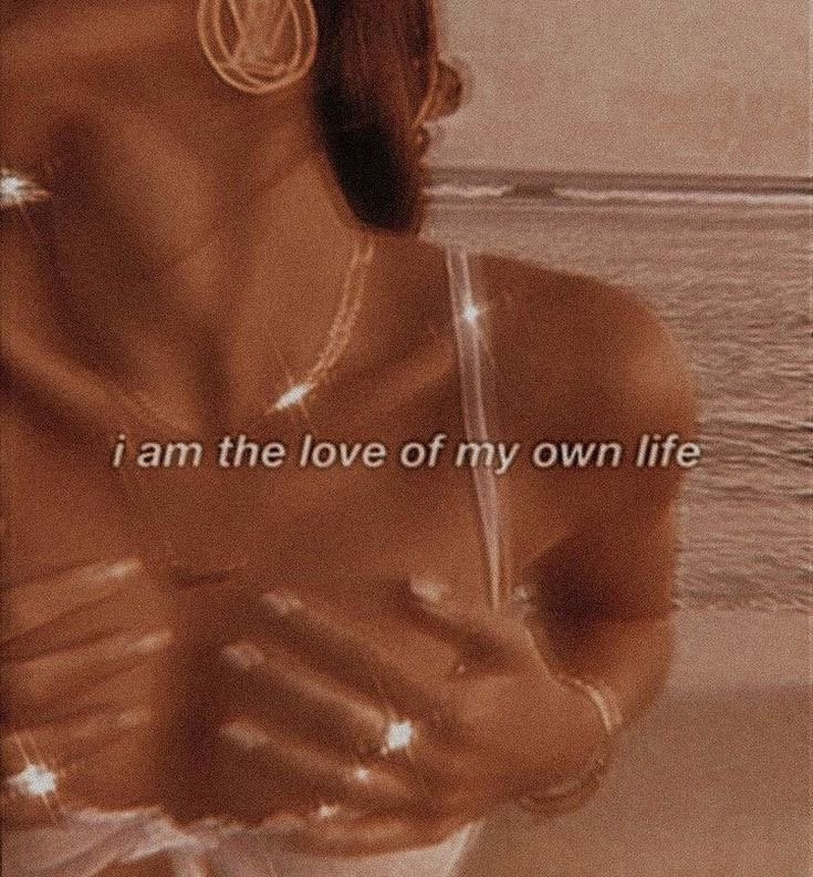 A woman wearing jewelry, with her face not visible, standing on a beach with the ocean in the background. The text reads "I am the love of my own life."