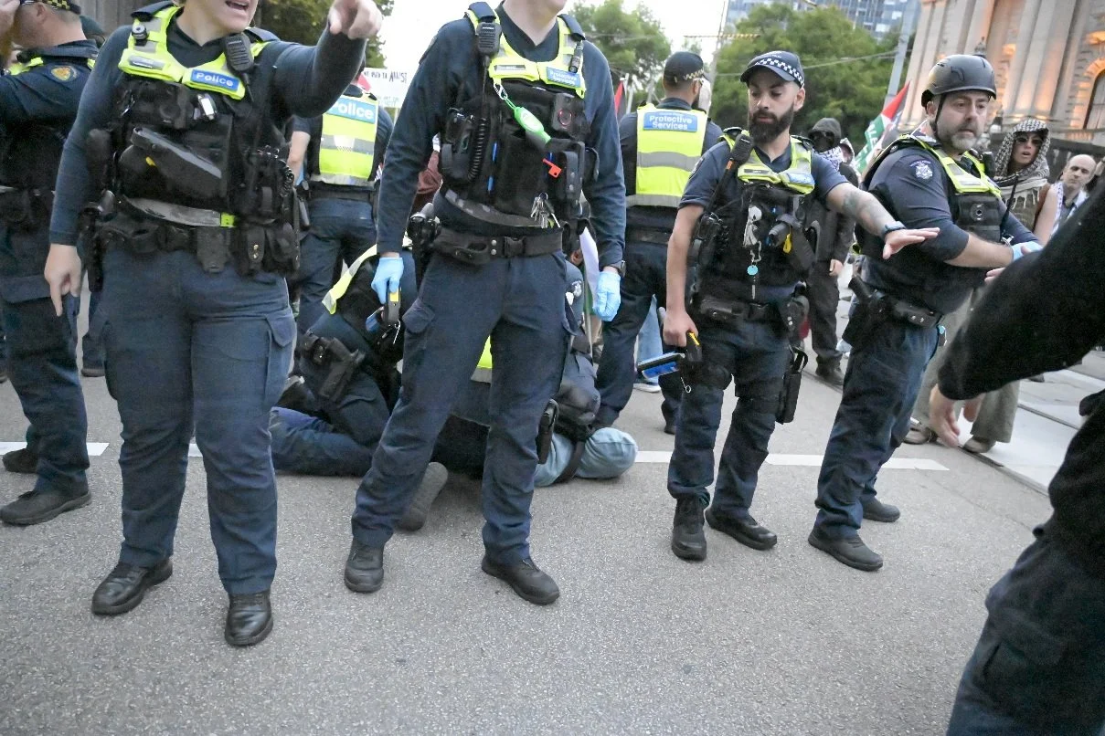 This documentary photograph was taken during a pro-Palestine march through Melbourne’s CBD, showing public protest, political symbolism, and everyday human moments within an urban demonstration. Photo by Farhad Rajabali