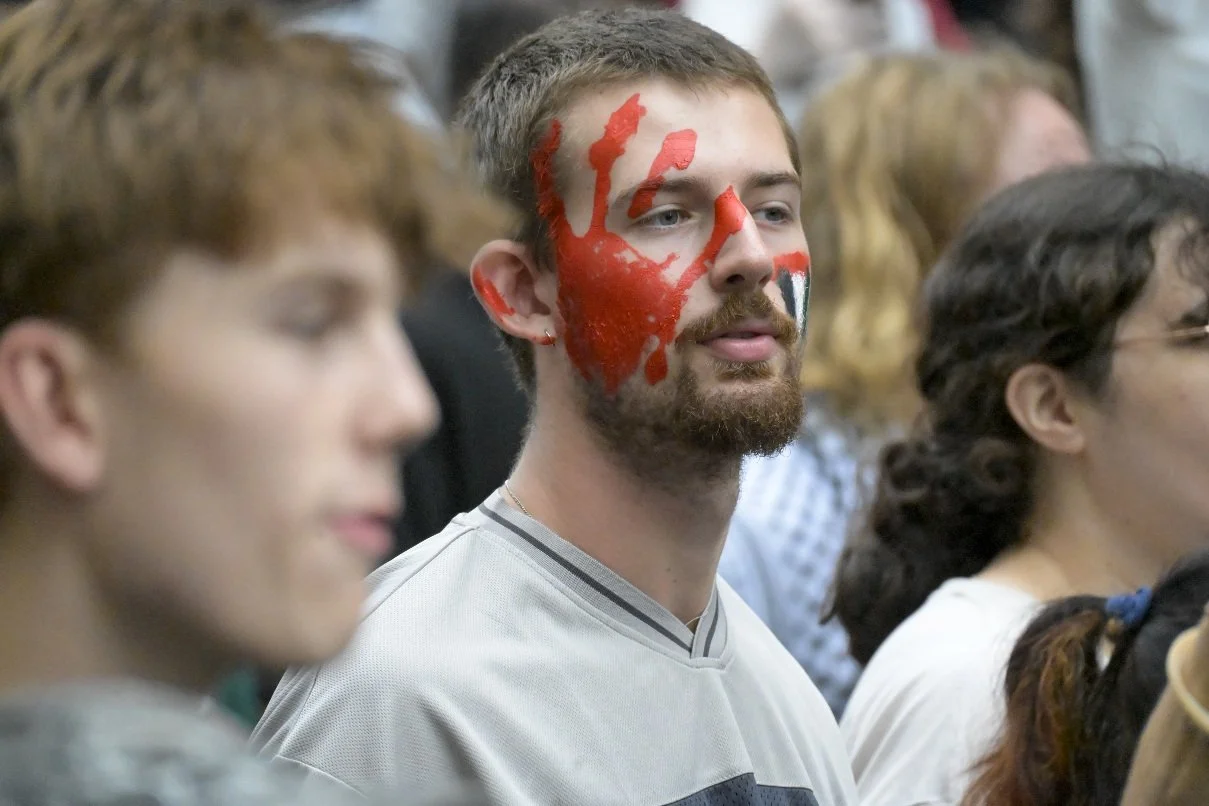 This documentary photograph was taken during a pro-Palestine march through Melbourne’s CBD, showing public protest, political symbolism, and everyday human moments within an urban demonstration. Photo by Farhad Rajabali