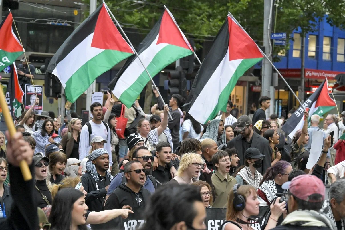 This documentary photograph was taken during a pro-Palestine march through Melbourne’s CBD, showing public protest, political symbolism, and everyday human moments within an urban demonstration. Photo by Farhad Rajabali