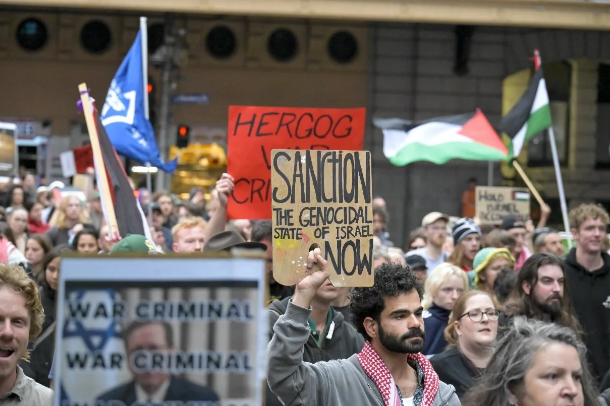 This documentary photograph was taken during a pro-Palestine march through Melbourne’s CBD, showing public protest, political symbolism, and everyday human moments within an urban demonstration. Photo by Farhad Rajabali