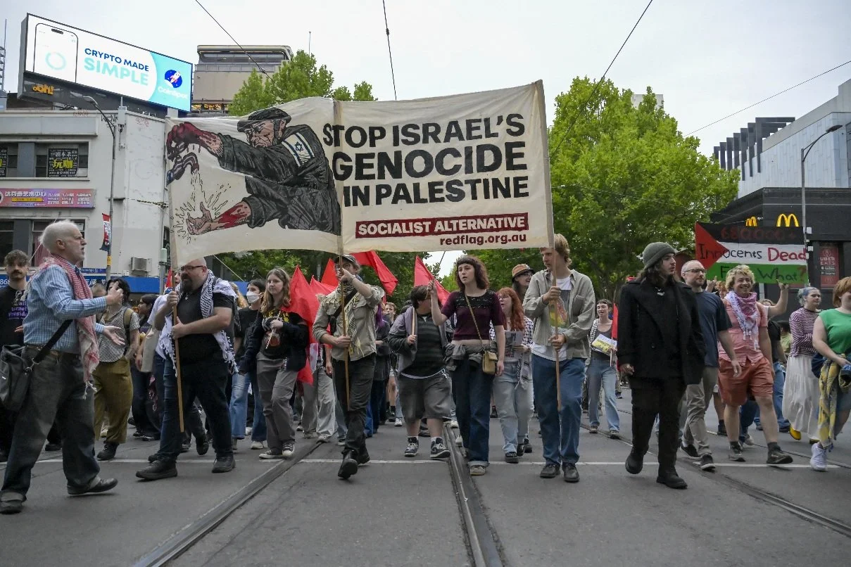 This documentary photograph was taken during a pro-Palestine march through Melbourne’s CBD, showing public protest, political symbolism, and everyday human moments within an urban demonstration. Photo by Farhad Rajabali