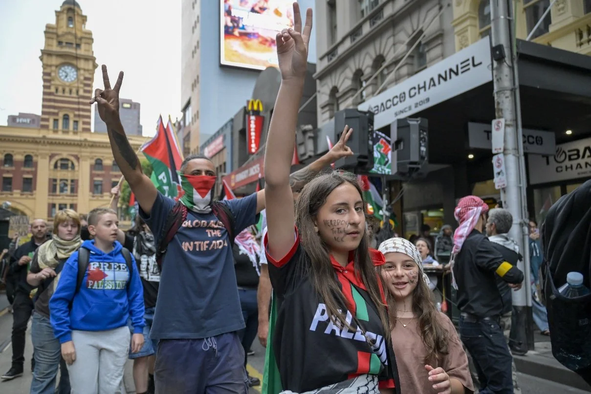 This documentary photograph was taken during a pro-Palestine march through Melbourne’s CBD, showing public protest, political symbolism, and everyday human moments within an urban demonstration. Photo by Farhad Rajabali