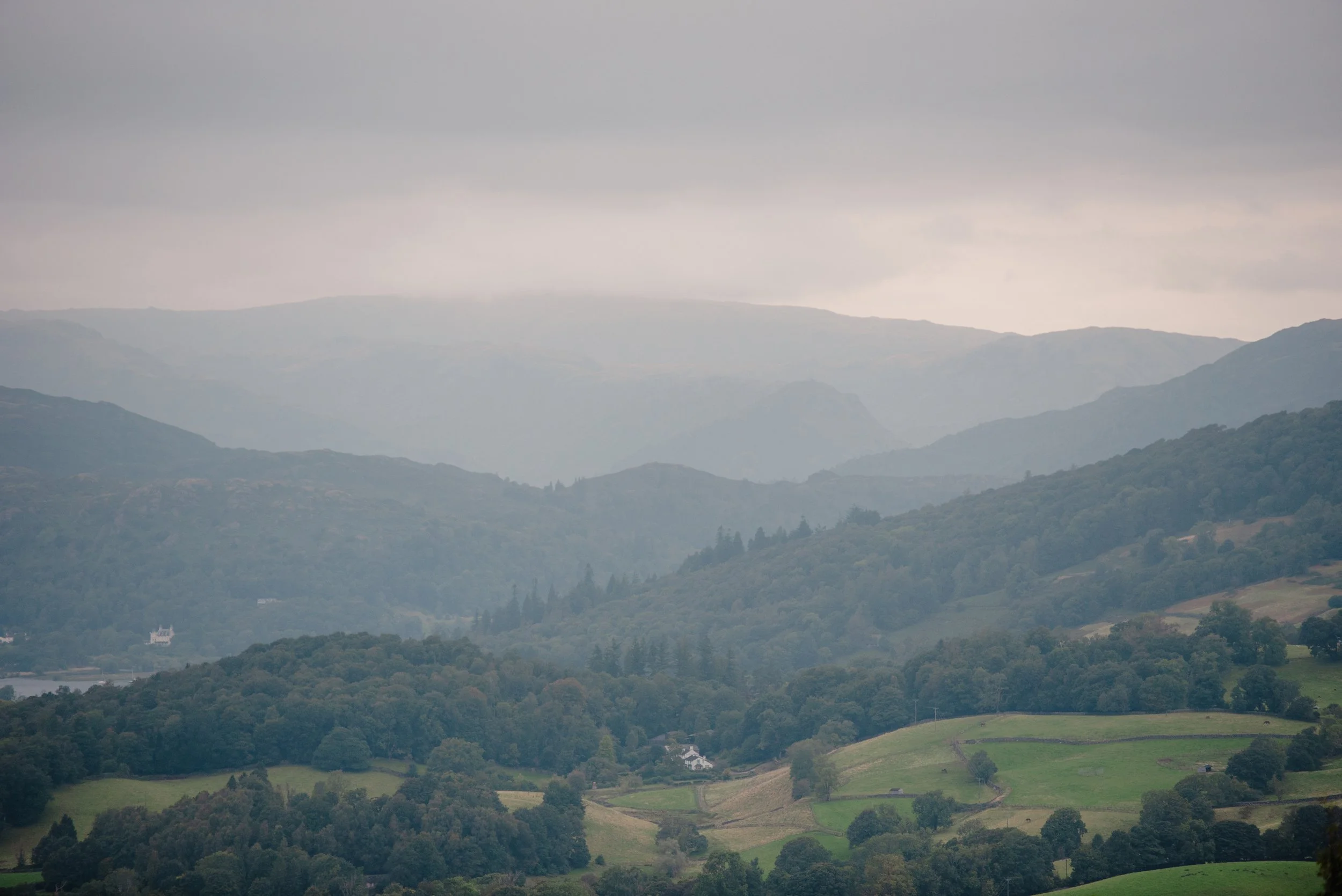 Overcast landscape of green rolling hills and distant mountains in the background.