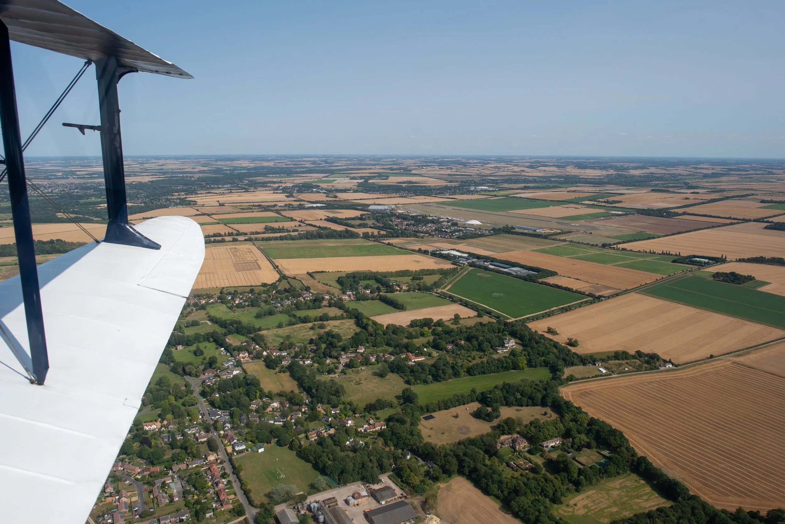 View from an airplane showing a patchwork of farmland and small towns below on a clear day.