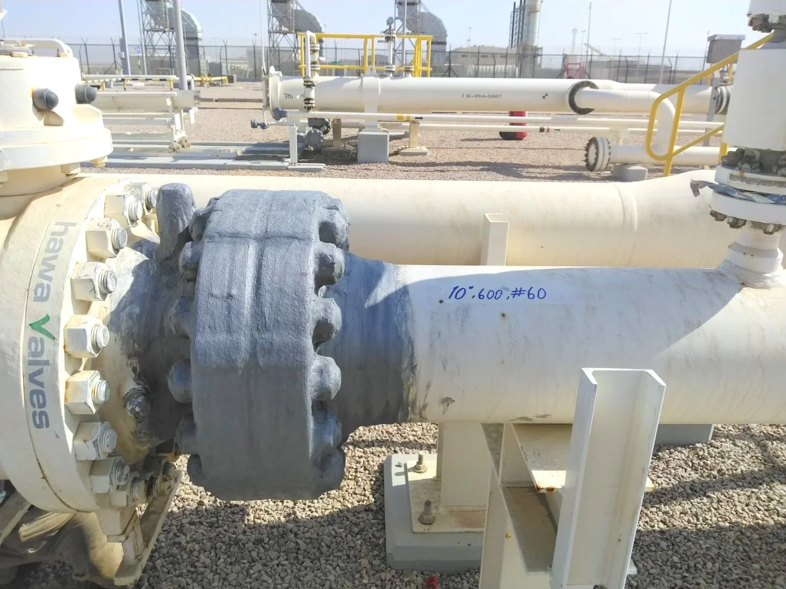 Large industrial pipeline with valve and bolts, part of a chemical or oil processing plant.