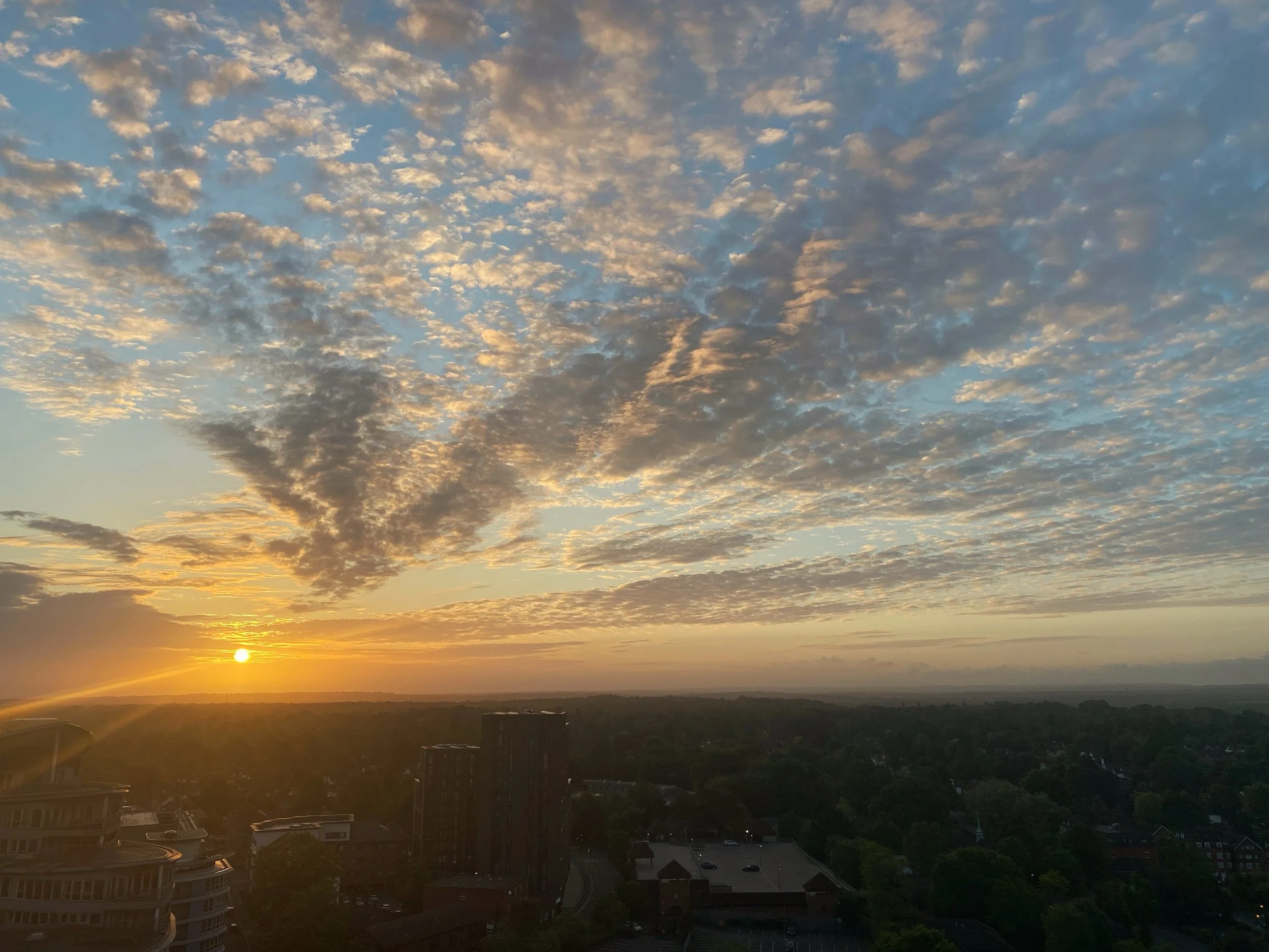 Sunset over a city with a partly cloudy sky.