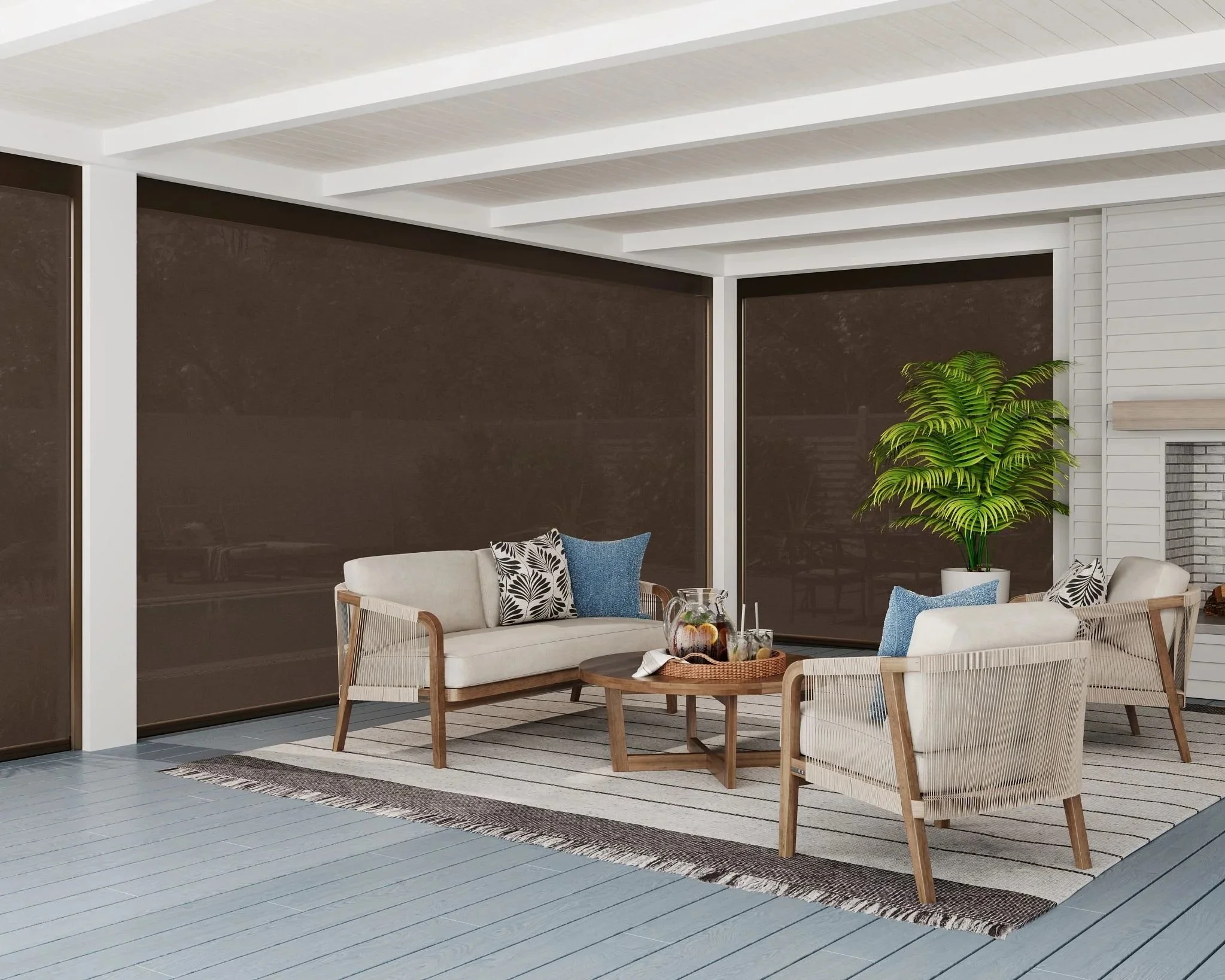 Modern outdoor patio with white wooden beams on the ceiling, a dark brown wall, and a white siding wall. There is a seating area with a white sofa, wooden chairs with white cushions, and patterned throw pillows. A small wooden table is in front of the sofa with a tray holding drinks and snacks. A large potted plant with green leaves is present, and a striped outdoor rug covers part of the light-colored wooden floor.