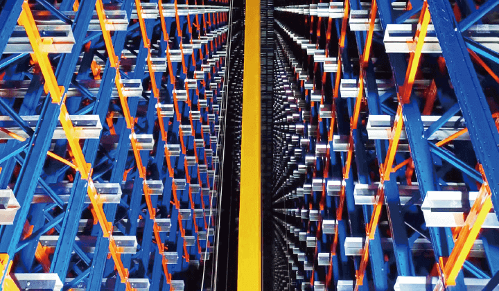 Inside a large warehouse, an advanced storage and retrieval system with blue and orange metal shelving and a yellow safety line on the floor.