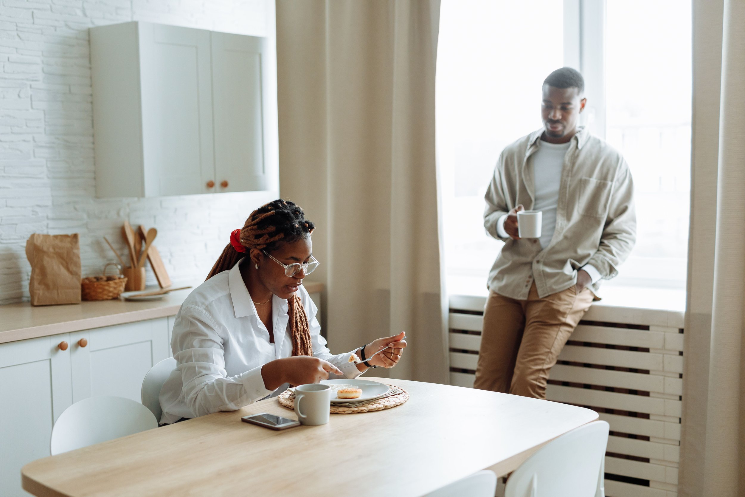 Couple in a sunlit kitchen on a weekend morning, one partner watching the other, illustrating relationship OCD doubt